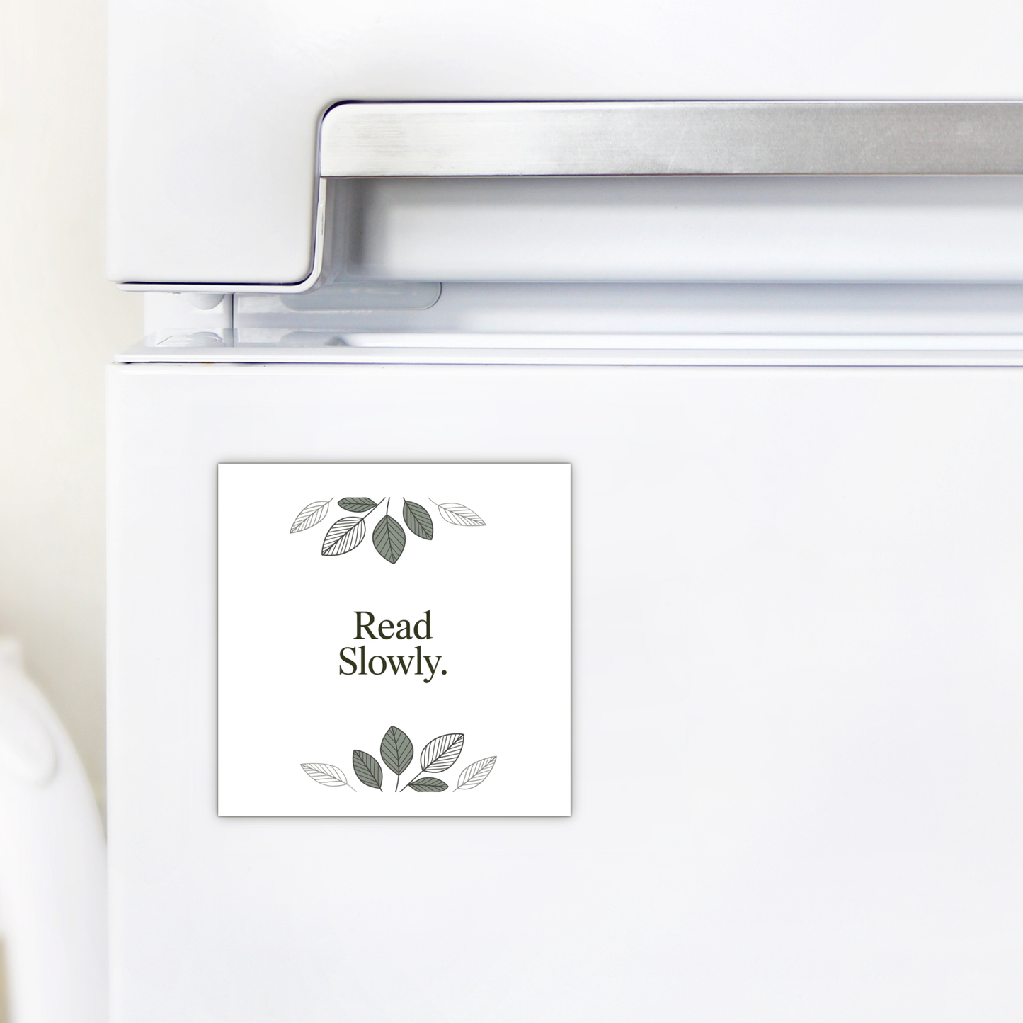 The Read Slowly Book Lover Magnet by Mirabilia Boutique features simple green and gray leaf illustrations—a charming literary decor piece and thoughtful gift for any book lover.