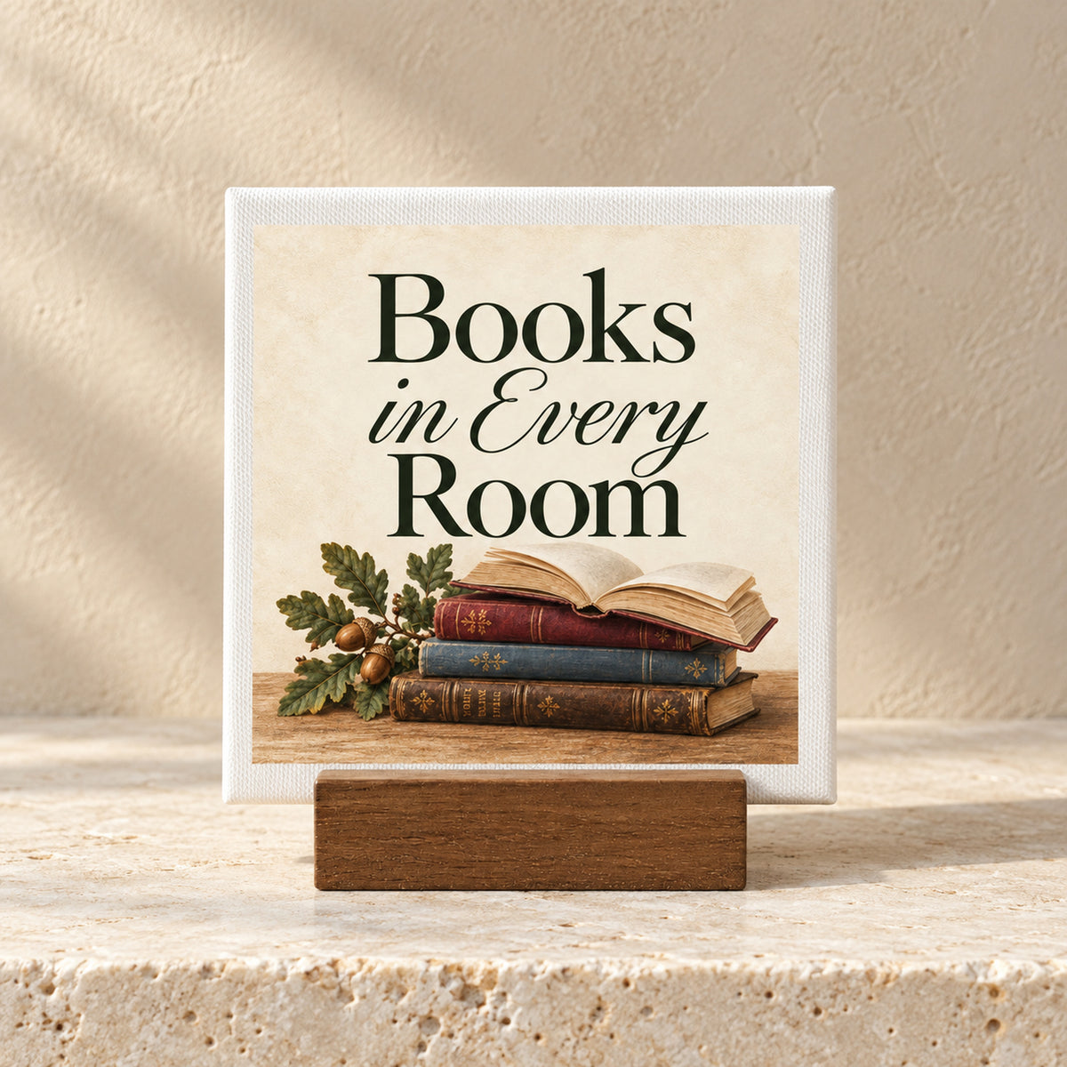 Books in Every Room Mini Sign on a wooden stand sits above a stack of vintage books and an acorn sprig.