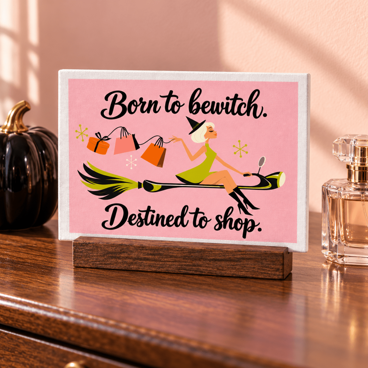 A Little Retail Magic Mini Sign | Fall Vibes featuring a retro witch riding a broomstick with shopping bags and the caption “Born to bewitch. Destined to shop.” on a wooden stand.