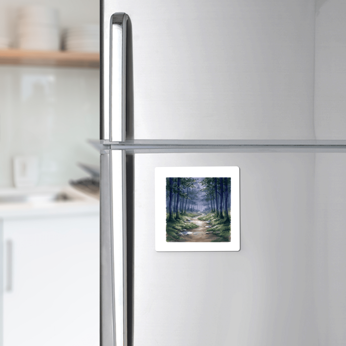 The Borrow a Little Moonlight Forest Magnet by Mirabilia Boutique—a square decorative magnet adorned with a painting of a forest path—is displayed on a stainless steel refrigerator in a modern kitchen, infusing the space with the charm of miniature artwork.