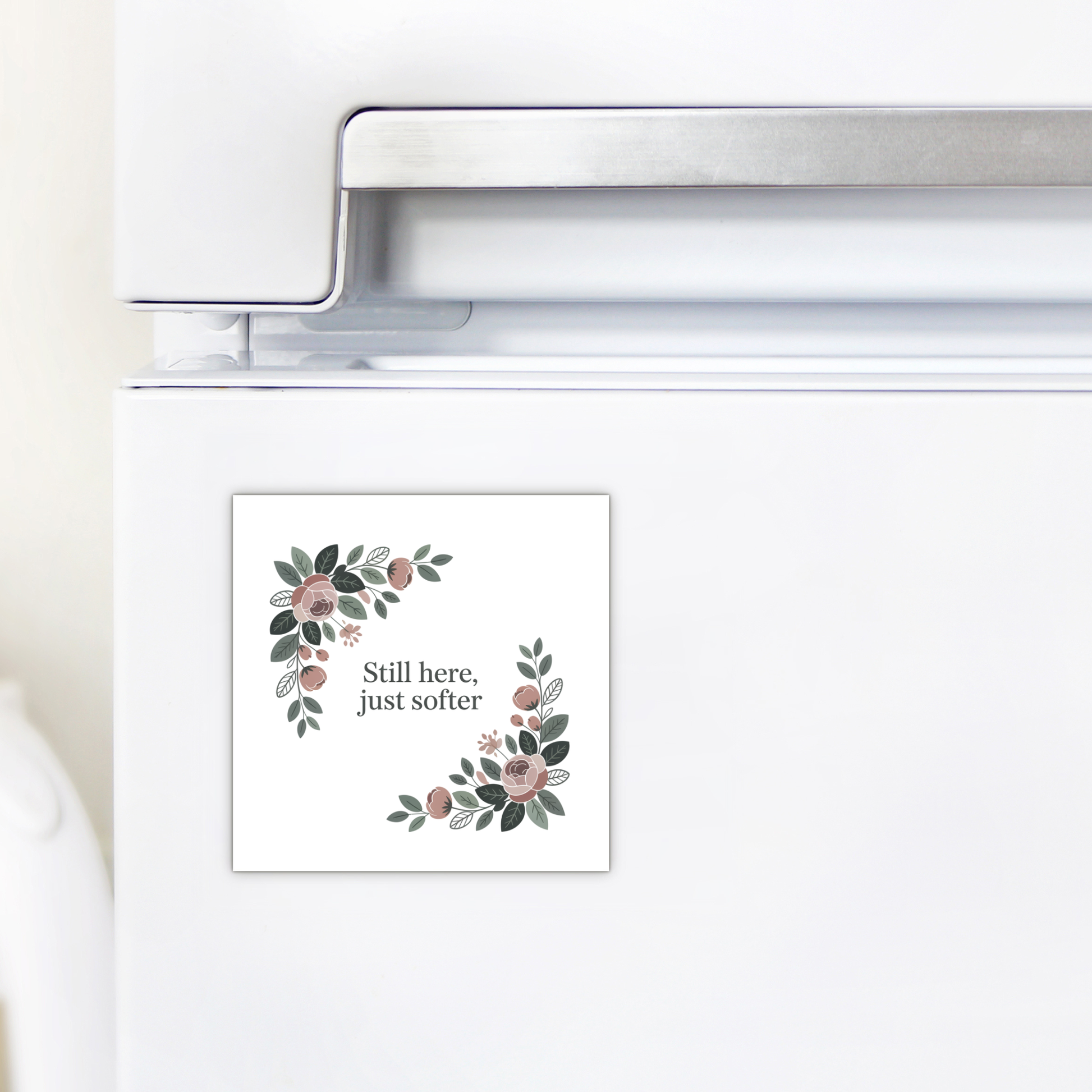 A white fridge displays the Mirabilia Boutique "Still Here Just Softer" Floral Magnet, featuring a botanical design—an ideal encouragement gift.