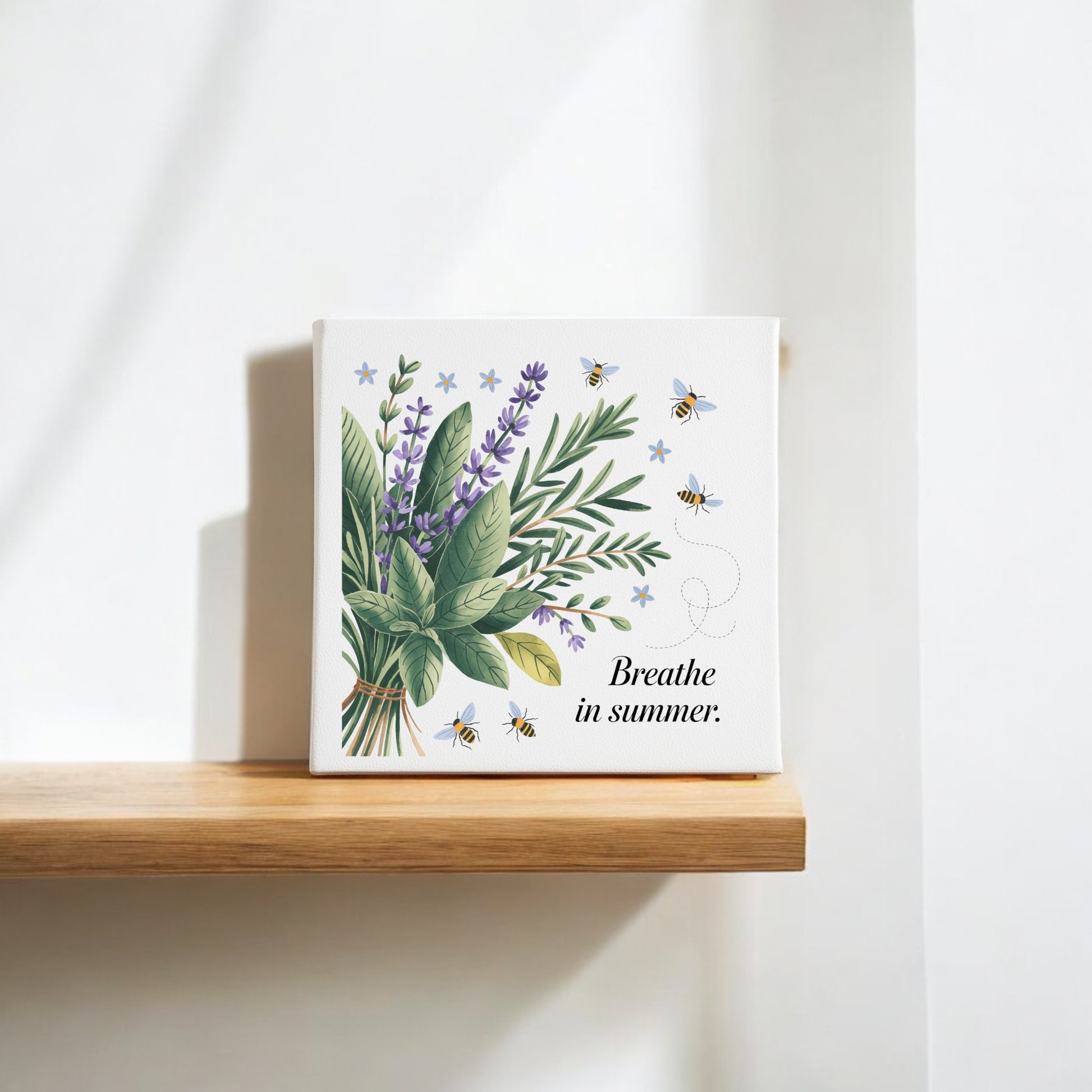 The Mirabilia Boutique "Breathe in Summer Canvas – Botanical Calm & Gentle Bees" features lavender, greenery, and bees with uplifting text, creating charming nature wall decor on a wooden shelf in bright natural light.