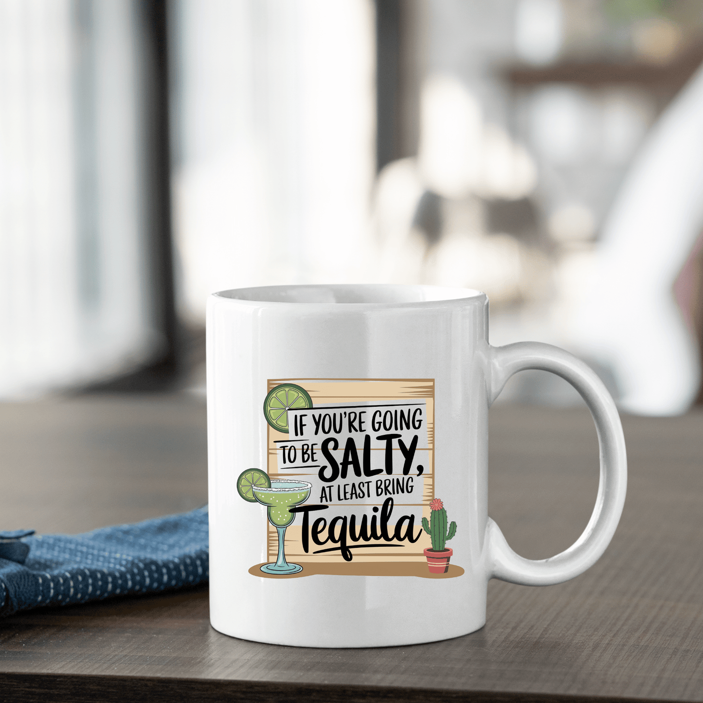 The Salty Tequila Mug – Funny Margarita Quote Coffee Cup by Mirabilia Boutique features a margarita, lime, cactus, and the phrase "If you're going to be salty, at least bring tequila." Perfect gift for anyone who loves playful mugs!.