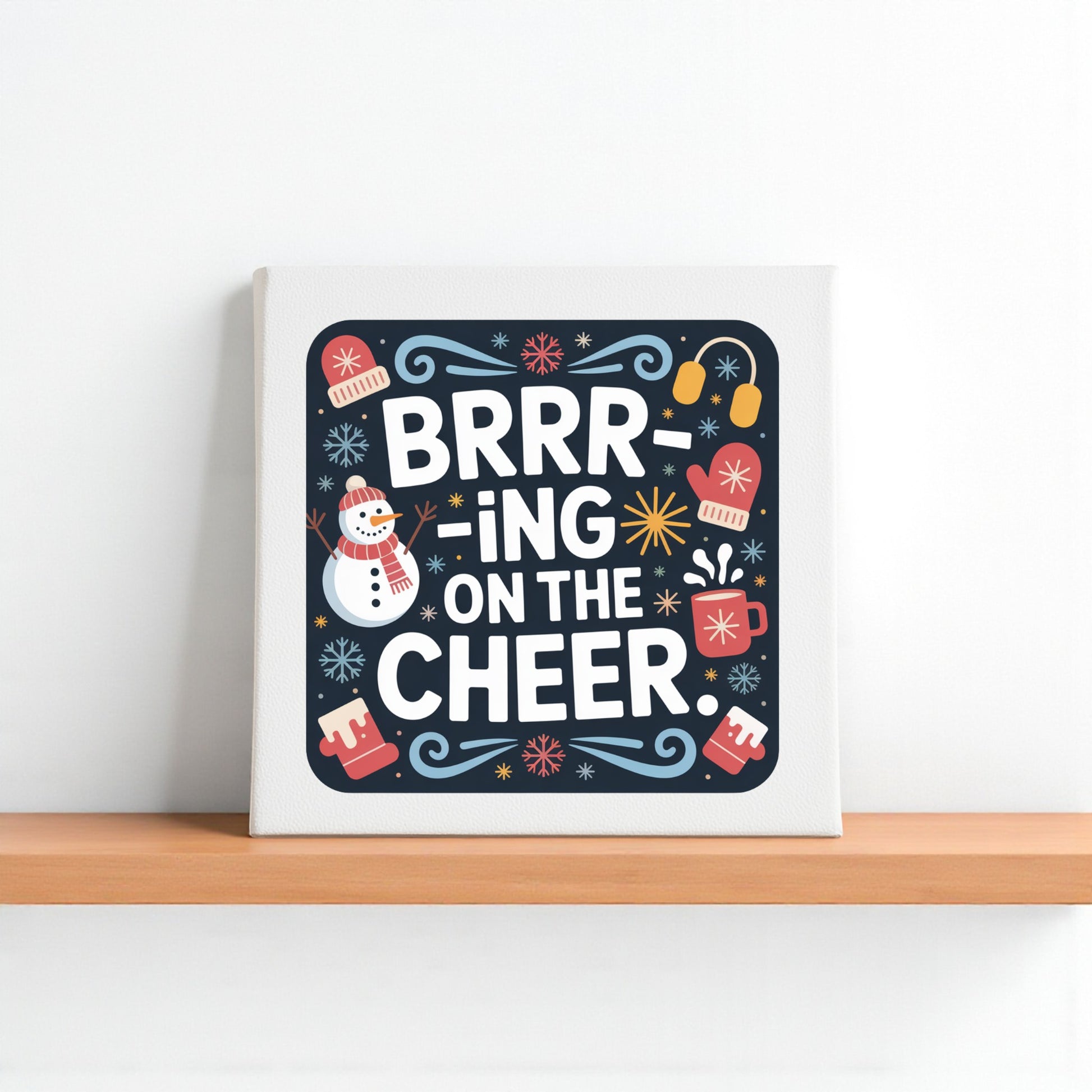 The Mirabilia Boutique “Brrr-ing on the Cheer Canvas” 8x8 holiday wall sign features a snowman, mugs, mittens, and festive accents—perfect winter or holiday home décor for any shelf or wall.