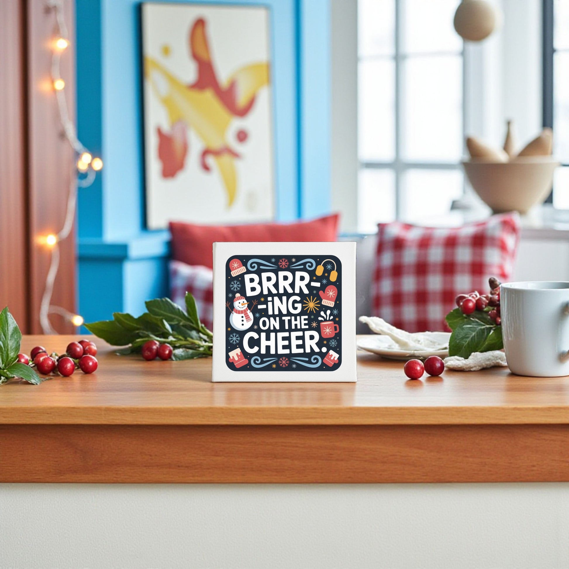 The 8x8 "Brrr-ing on the Cheer" Canvas by Mirabilia Boutique features festive winter art and brightens your holiday space—perfect amid cozy pillows, holly, mugs, and seasonal decor to capture the joy of the season.