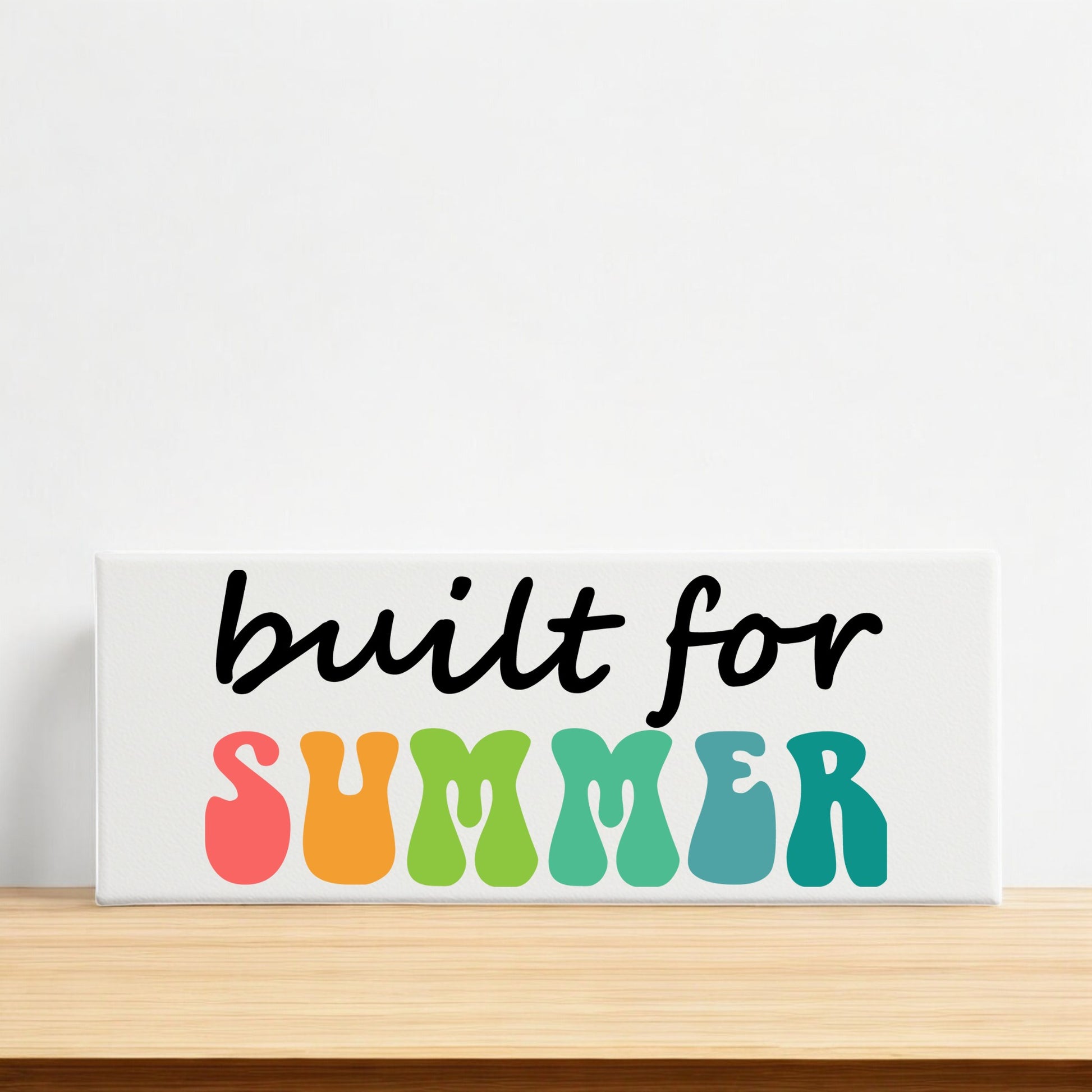 The Built for Summer Canvas – Retro Shelf Sign by Mirabilia Boutique features bold, colorful wavy letters, making it a vibrant summer decor piece perfect for brightening any mantle or shelf.