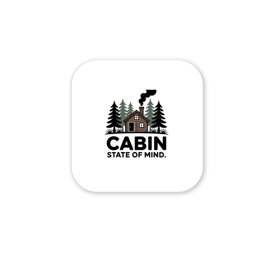 The Cabin State of Mind Magnet by Mirabilia Boutique features a cabin amid pines with chimney smoke, and bold "CABIN STATE OF MIND" text. Ideal as rustic cabin decor or woodland home accessory, it comes on a rounded square white background.
