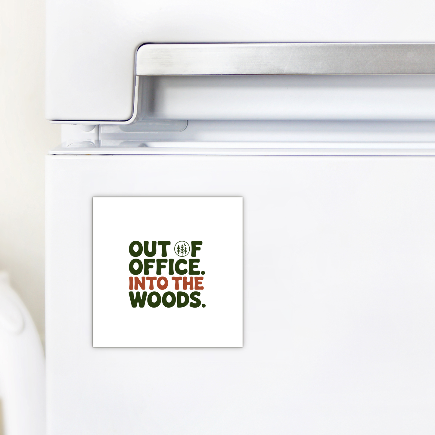 A white refrigerator displays the Mirabilia Boutique "Out of Office Into the Woods Magnet," featuring green and brown text with a tree-shaped "O"—a perfect nature-themed cabin decor for adventurers.