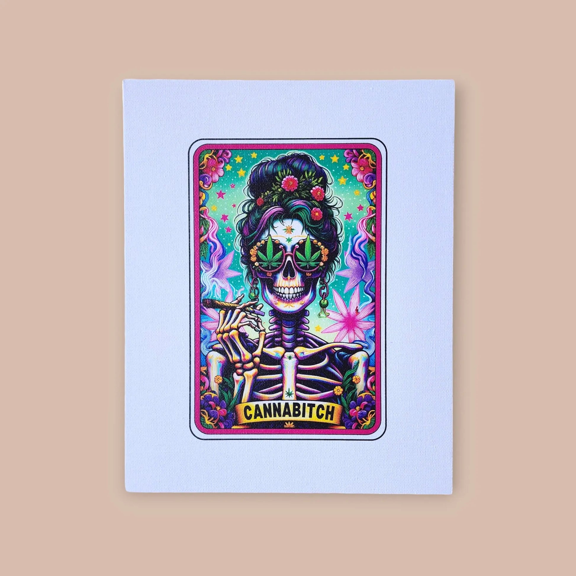 The Cannabitch 8x10 Canvas Sign from Mirabilia Boutique showcases a vibrant artwork of a skeleton with an updo adorned with flowers and sunglasses shaped like marijuana leaves. The skeleton is holding a joint and smiling, while the bottom of the canvas prominently displays "CANNABITCH." The background is filled with vibrant colors and patterns that evoke the style of tarot card designs.