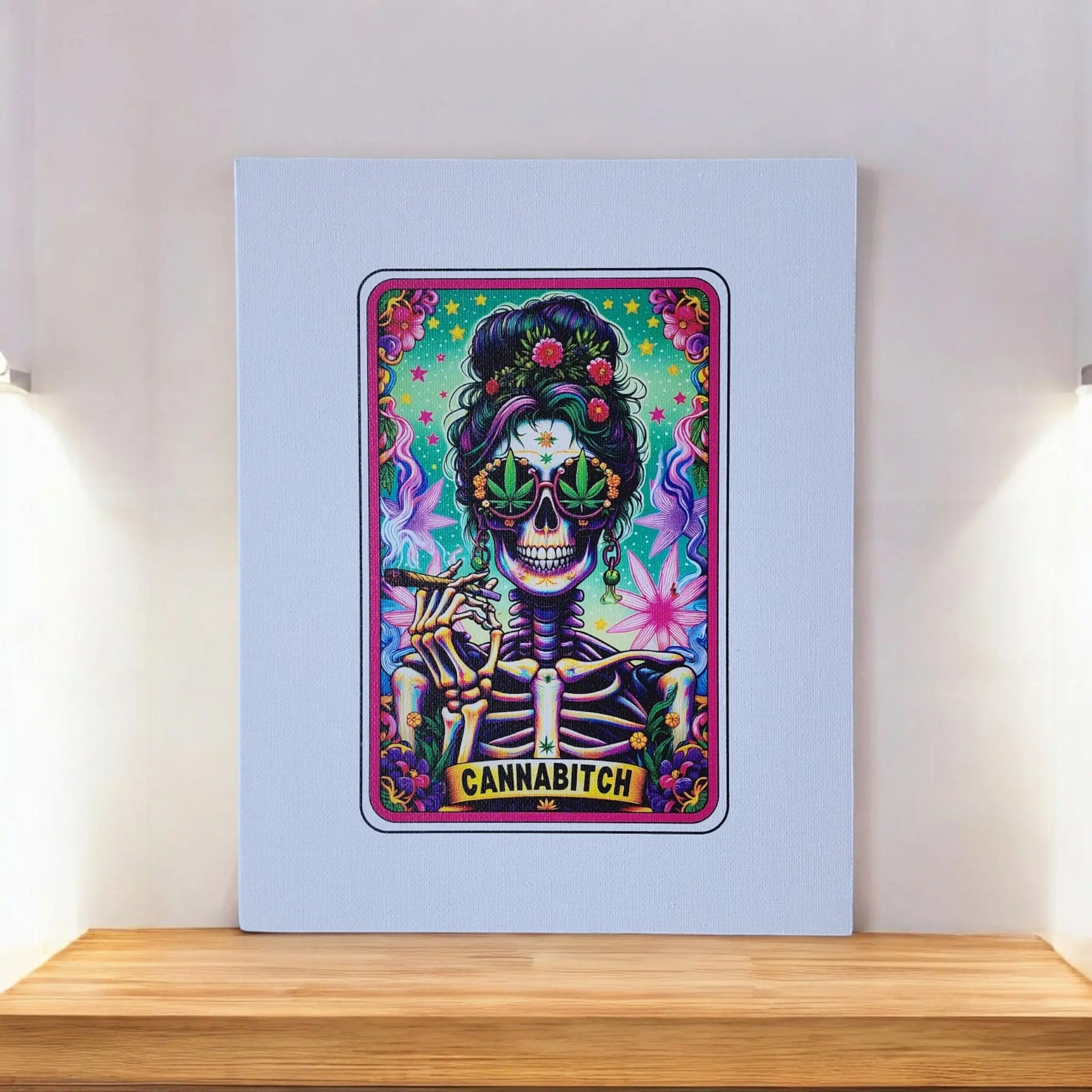 The Mirabilia Boutique Cannabitch 8x10 Canvas Sign showcases a vibrant artwork that evokes the style of a tarot card. It depicts a skeleton with a stylish beehive hairdo, donning floral sunglasses and holding a cannabis leaf, with the word "CANNABITCH" prominently displayed at the bottom. The artwork is printed on white canvas and beautifully positioned on a wooden shelf.