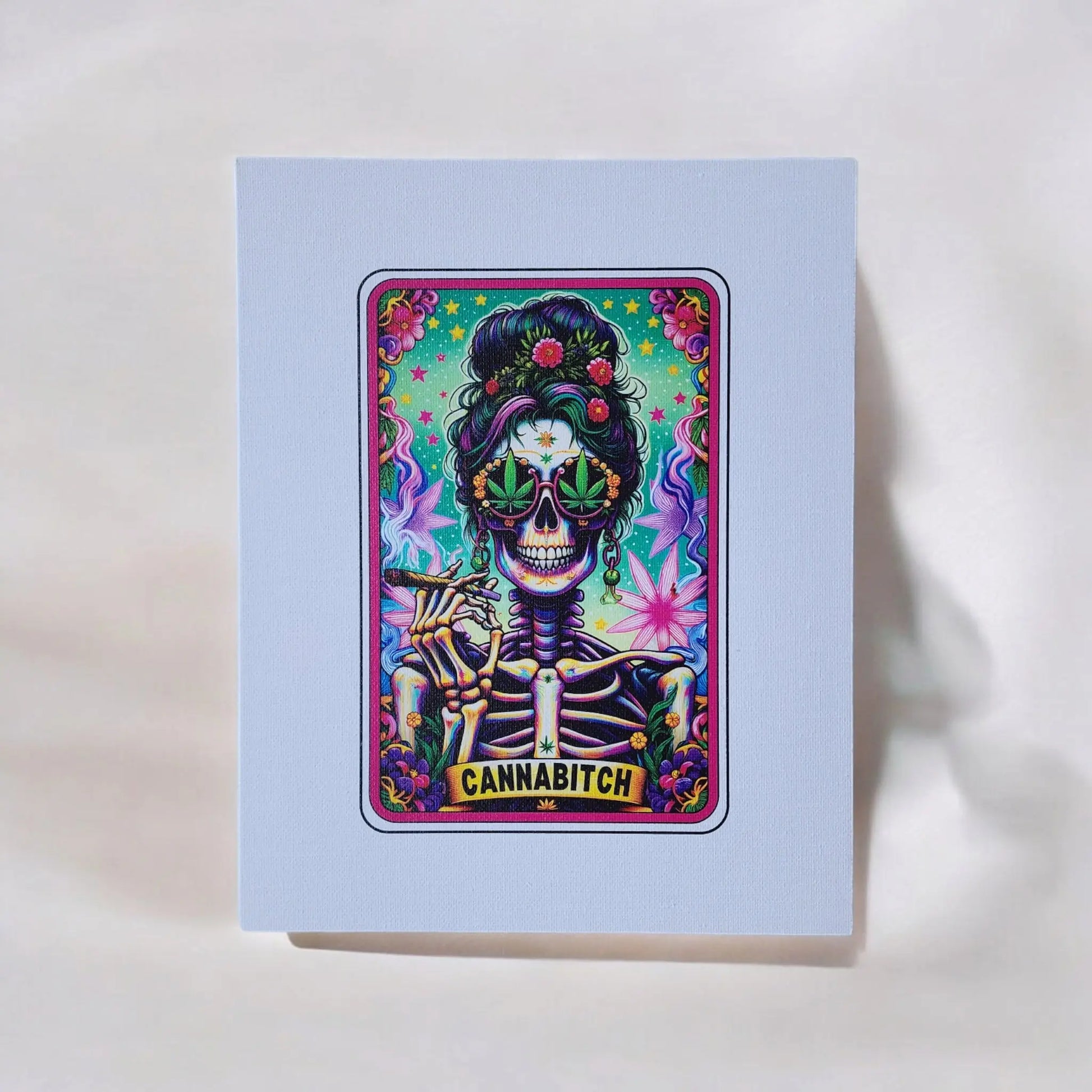The Cannabitch 8x10 Canvas Sign from Mirabilia Boutique features a dynamic tarot card-style artwork showcasing a skeleton with vibrant, rolled hair. The skeleton wears large sunglasses shaped like cannabis leaves and holds a lit joint, set against an energetic backdrop of neon colors and cannabis leaves. The word "CANNABITCH" is prominently displayed in the design.