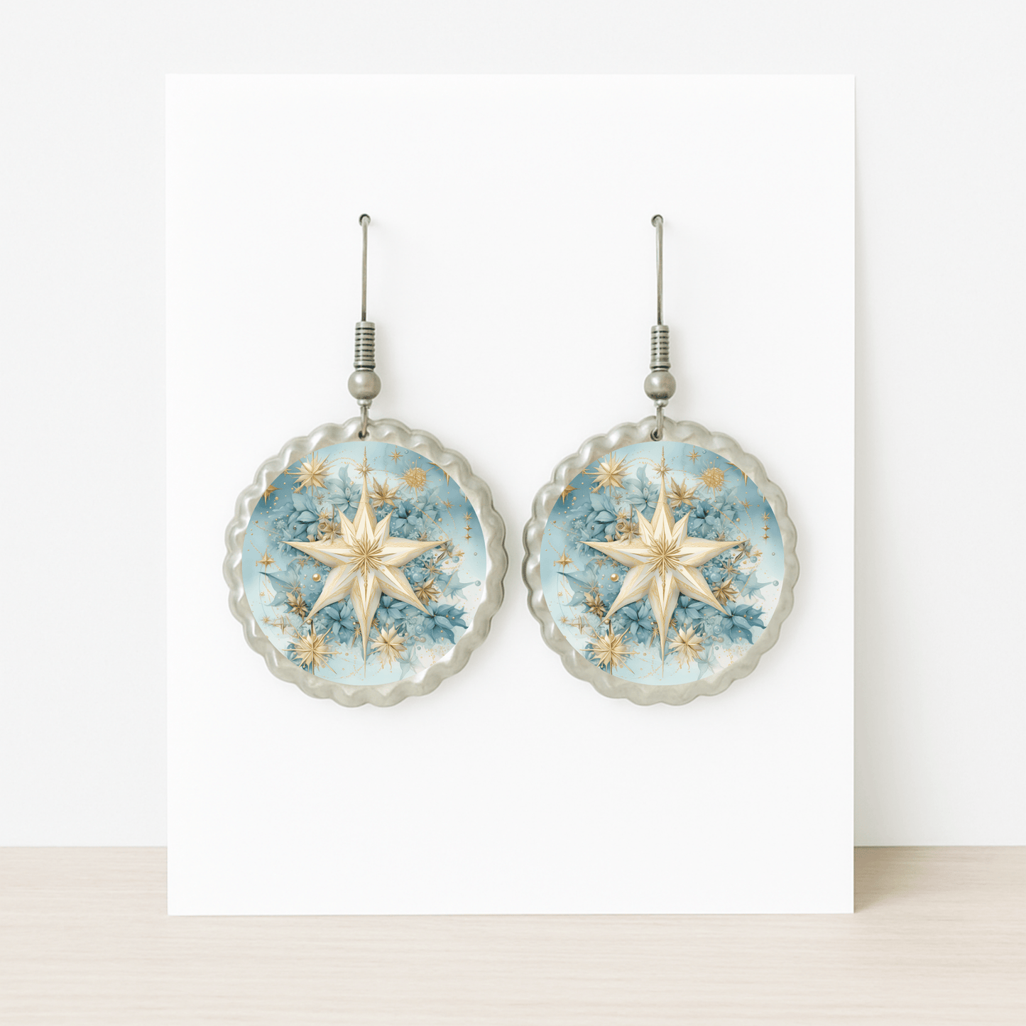 Celestial Star Earrings by Mirabilia Boutique: Blue floral dangle earrings with scalloped edges and a golden star motif, displayed on a white card atop a light wood surface.