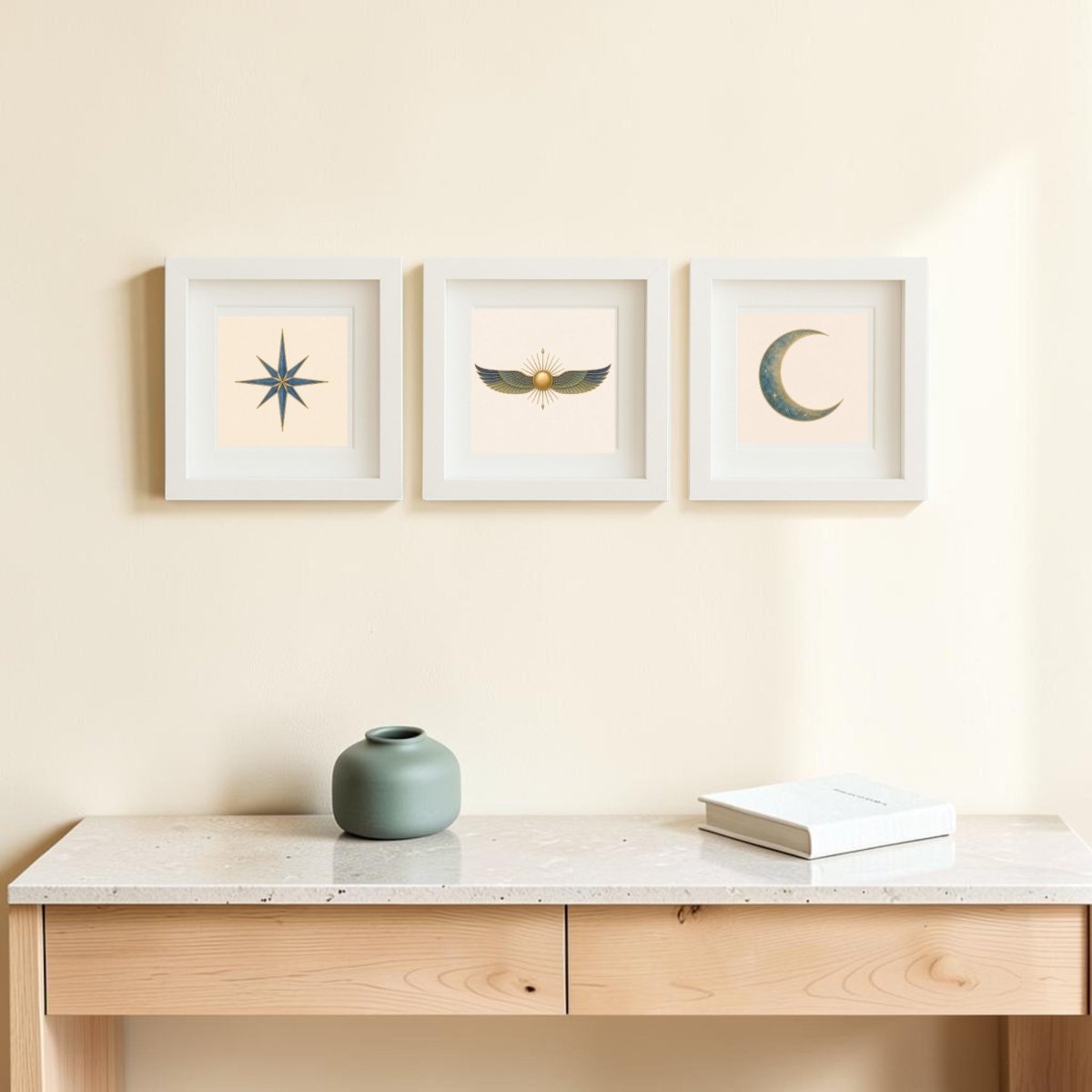 Three framed pieces from Mirabilia Boutique’s “Celestial Relics of the Nile | Mirabilia Relics” canvas art collection hang above a light wooden desk, each featuring striking celestial designs—a compass star, a winged sun, and a crescent moon. A green vase and a closed book rest on the desk, rounding out the tranquil scene.