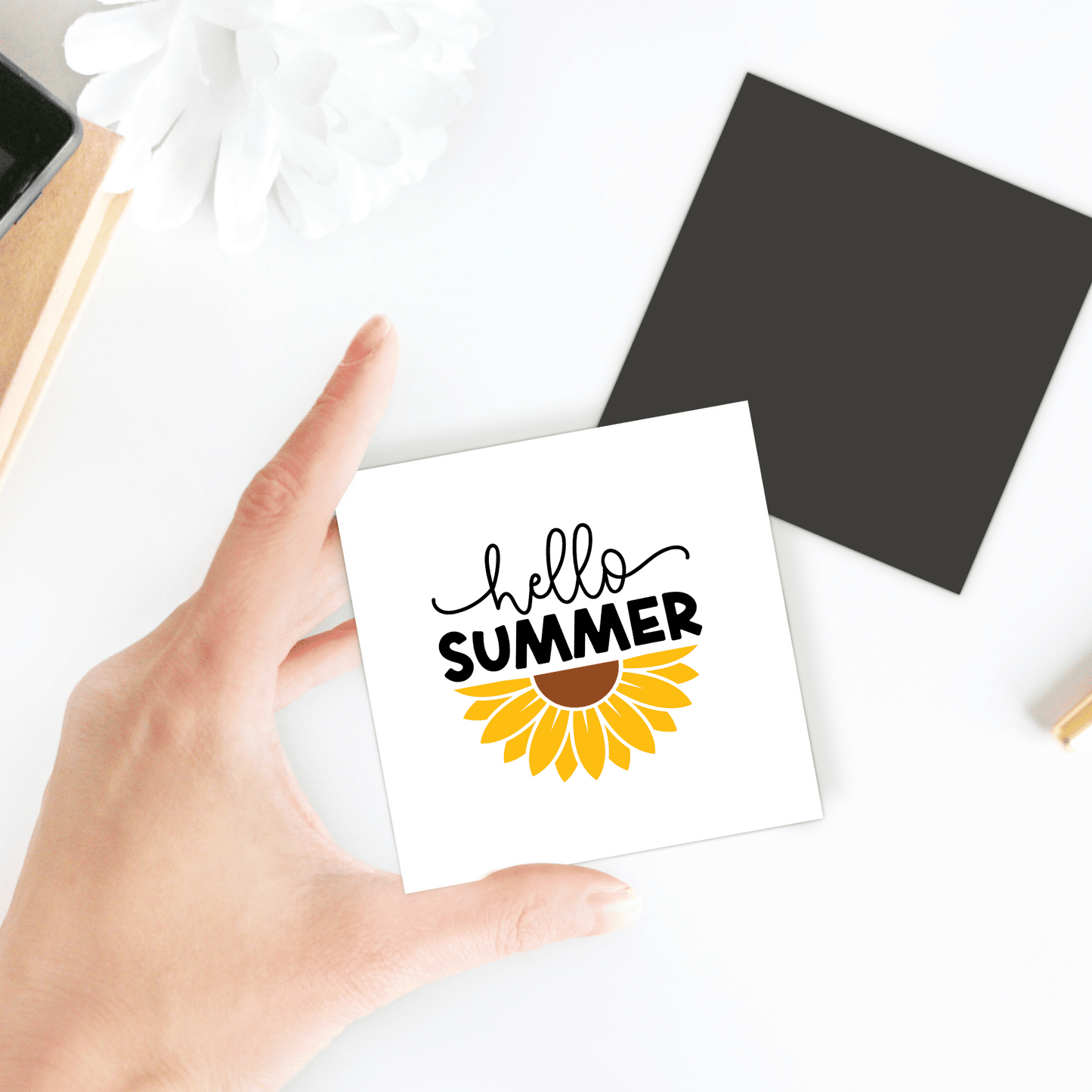 A hand displays the Mirabilia Boutique Hello Summer Sunflower Magnet – Bright Floral Fridge Art, featuring a cheerful sunflower and "hello SUMMER" text; perfect as a summer gift or decorative fridge magnet.