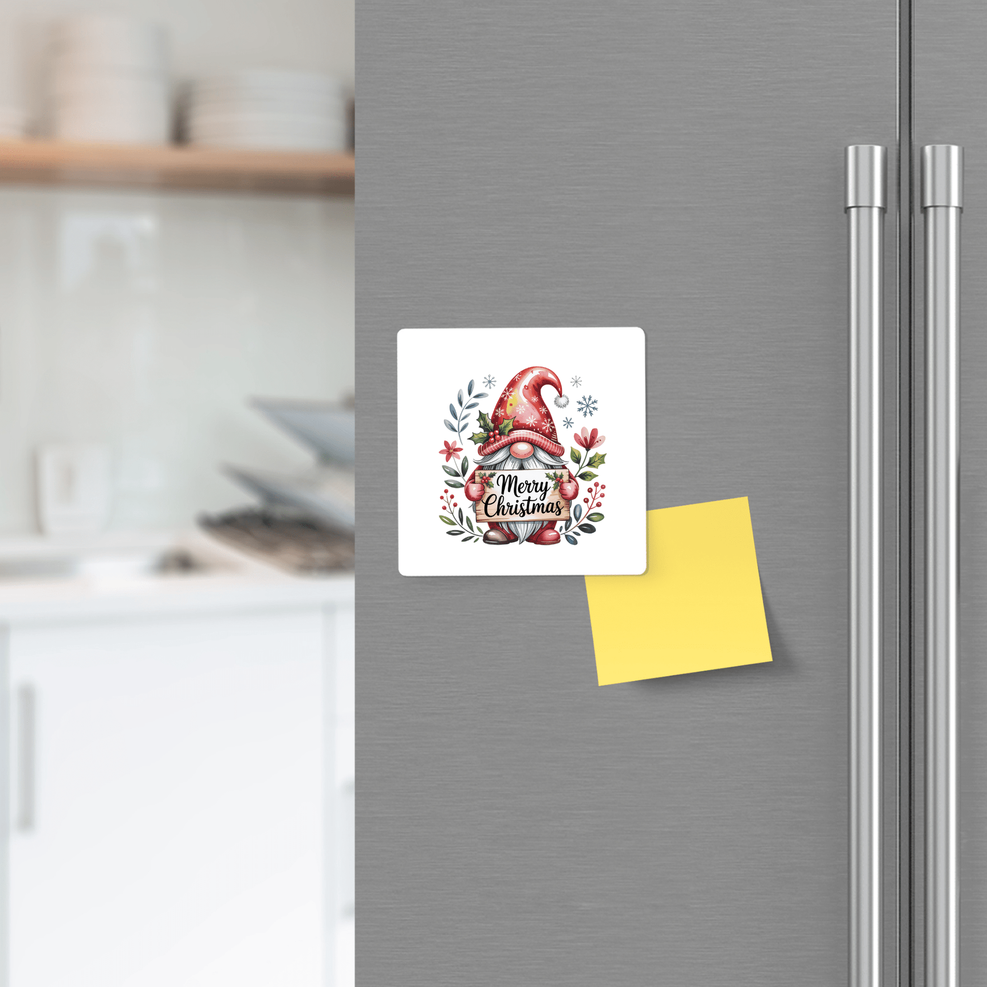 The Mirabilia Boutique Merry Christmas Gnome Magnet adds festive charm to a silver fridge. This square holiday decor is the perfect stocking stuffer, with a yellow sticky note below and kitchen dishes visible in the background.