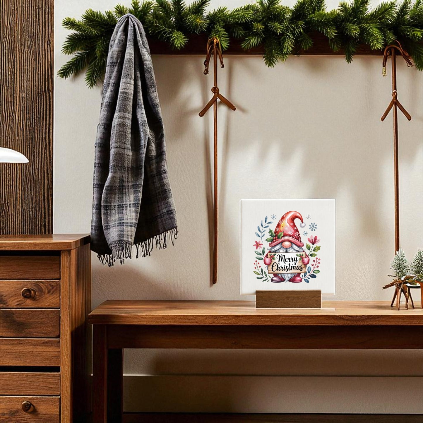 A cozy room with a wooden bench and hooks, plaid scarf, pine garland above, and the Mirabilia Boutique Christmas Gnome Mini Sign (4x4 Canvas Holiday Decor) adding festive holiday charm displayed on the bench.