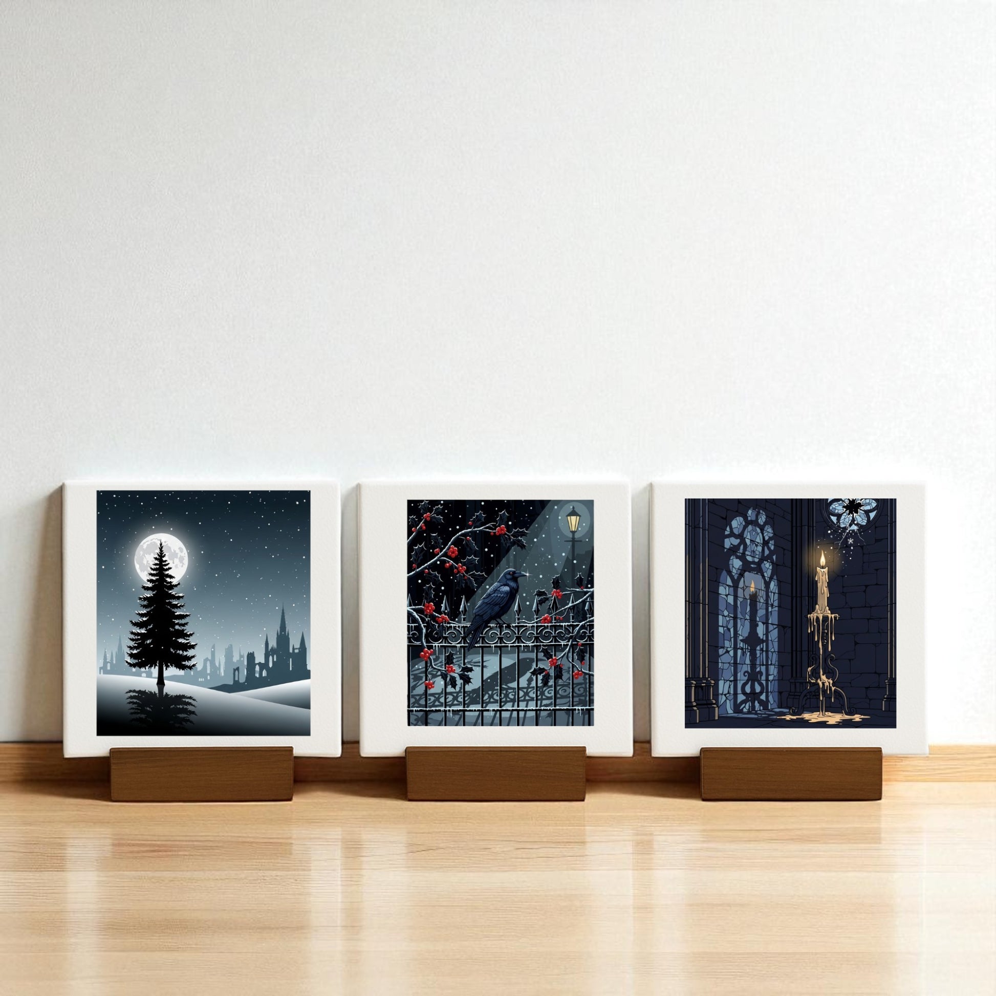 The Christmas Noir Midnight Trio by Mirabilia Boutique features three square prints on wooden stands—a moonlit tree, a raven with red berries, and a candle in a gothic window—ideal gothic holiday decor for your Christmas Noir Mini Canvas collection.