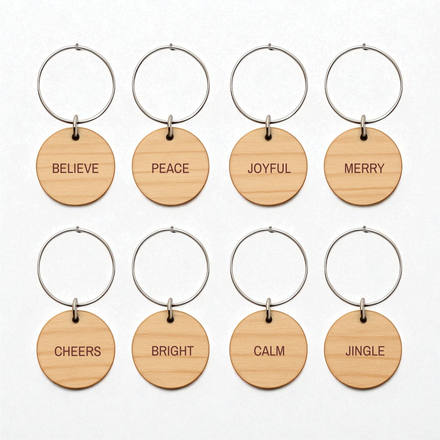 Mirabilia Boutique’s Christmas Wine Charms | Wood Holiday Glass Markers Set includes eight round wooden keychains with metal rings, each engraved with a festive word—perfect for marking glasses at your holiday gatherings.