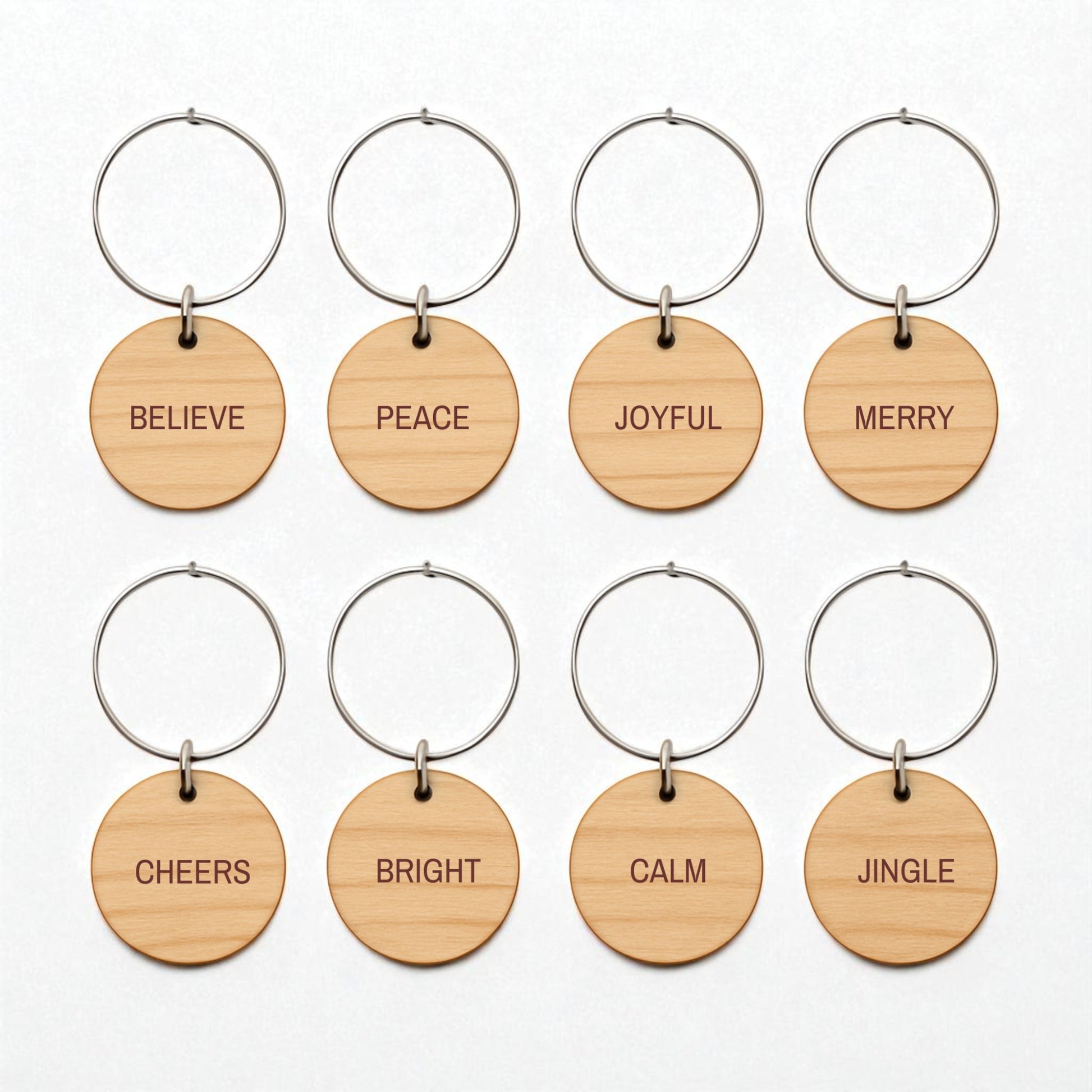 Mirabilia Boutique’s Christmas Wine Charms | Wood Holiday Glass Markers Set includes eight round wooden keychains with metal rings, each engraved with a festive word—perfect for marking glasses at your holiday gatherings.
