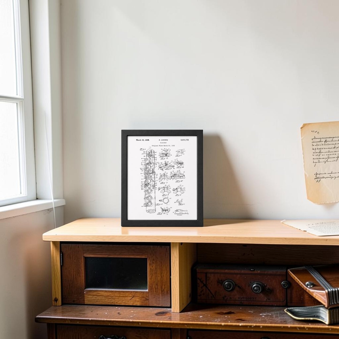 The Clarinet Patent Print on Metal Wall Art by Mirabilia Boutique sits on a light wooden cabinet by a window, with a handwritten letter pinned above—an elegant touch for music room decor.