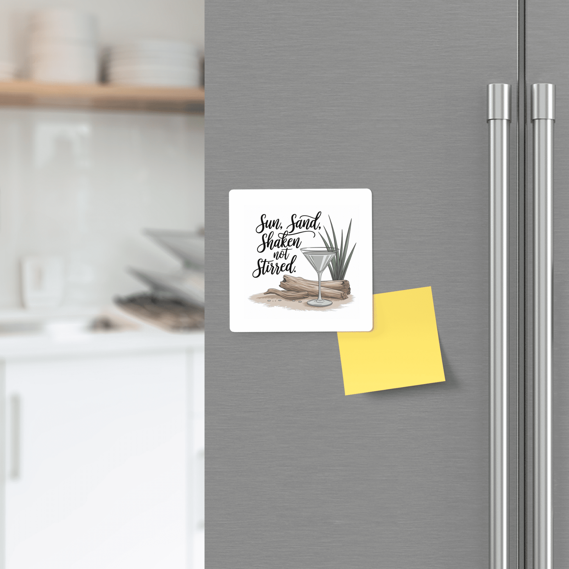 The Mirabilia Boutique Sun, Sand, Shaken Not Stirred Magnet – Coastal Cocktail Quote adds coastal charm to any stainless steel fridge, featuring a fun cocktail design and quote beside a yellow sticky note in a bright kitchen.