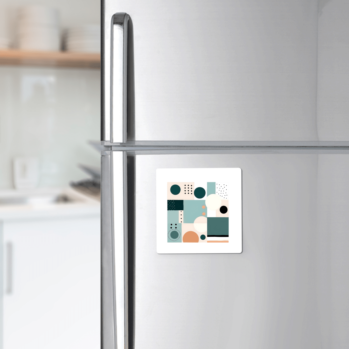 A silver refrigerator in a kitchen with the Coastal Geometry Mid Century Modern Magnet by Mirabilia Boutique, featuring an abstract geometric design in teal, beige, black, and white.