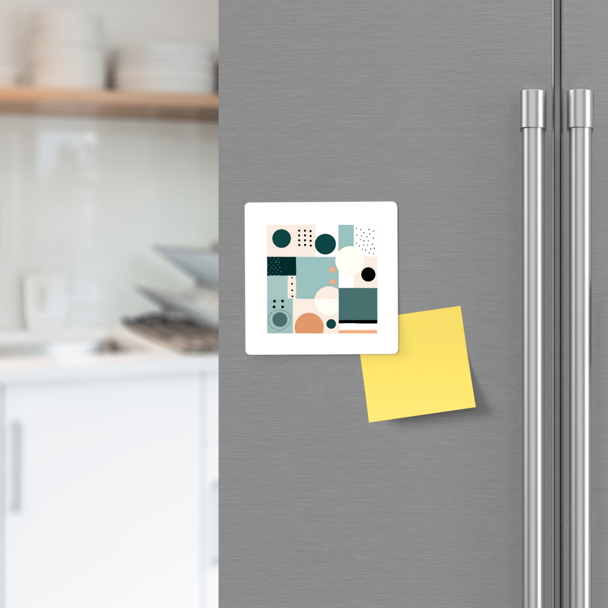 A gray refrigerator door features the Coastal Geometry Mid Century Modern Magnet by Mirabilia Boutique and a yellow sticky note. Blurred kitchen shelves and dishes in the background enhance the modern, coastal-inspired decor.