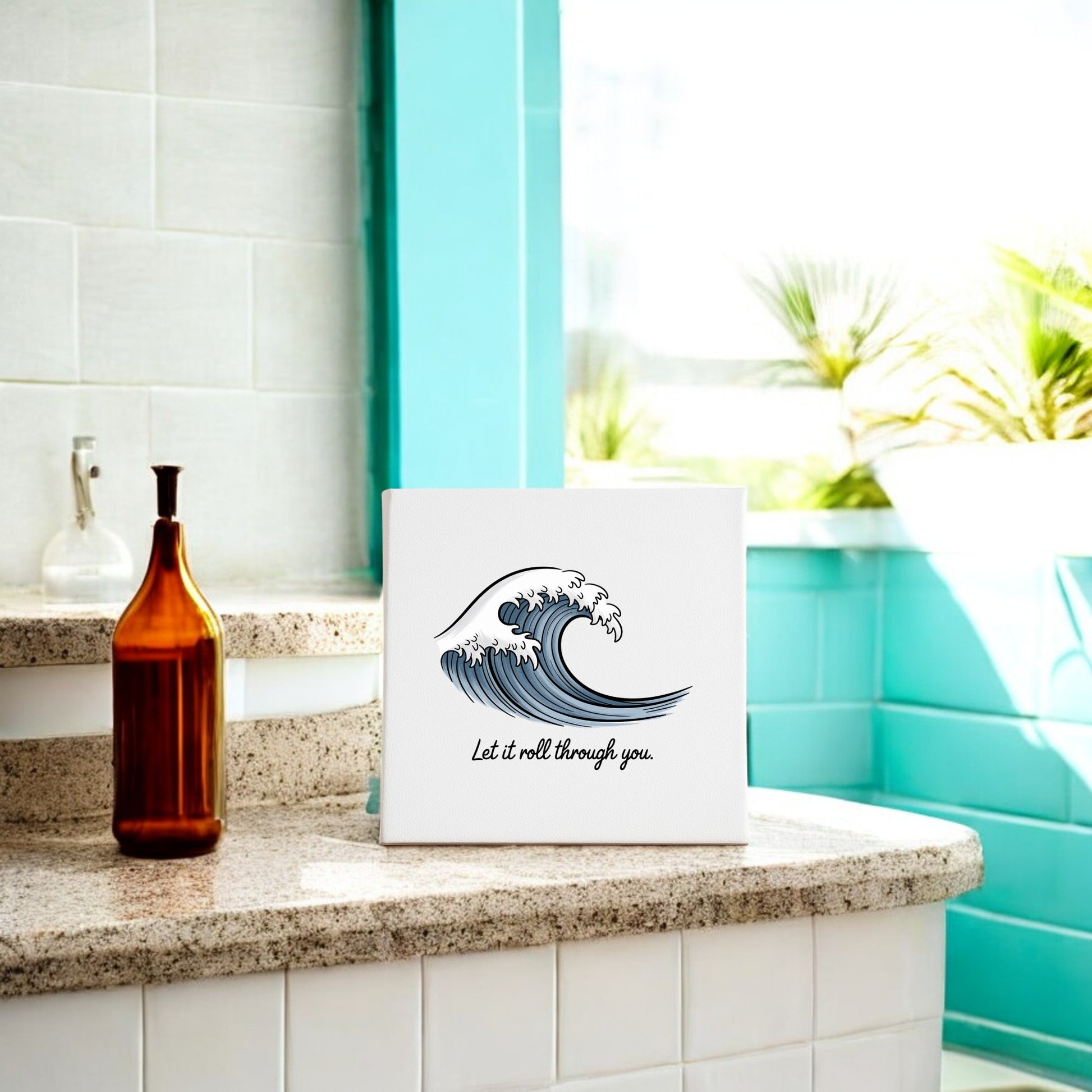The Let It Roll Through You Canvas – Ocean-Inspired Calm by Mirabilia Boutique sits on a bathroom counter with a brown glass bottle, against turquoise tiles—an inspirational wall art piece perfect for meditation decor in your sunlit space.