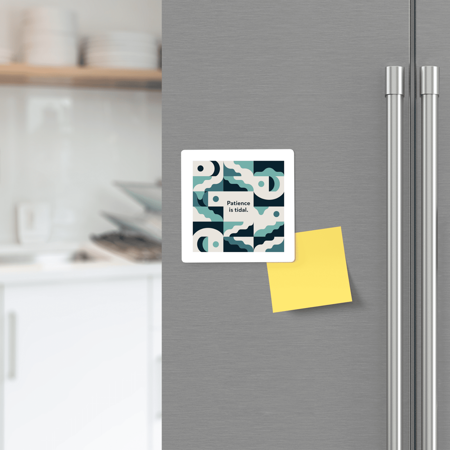 A Mirabilia Boutique "Patience Is Tidal Magnet – Ocean-Inspired Calm Quote" with blue and white patterns is displayed on a stainless steel fridge beside a yellow sticky note in a modern kitchen.