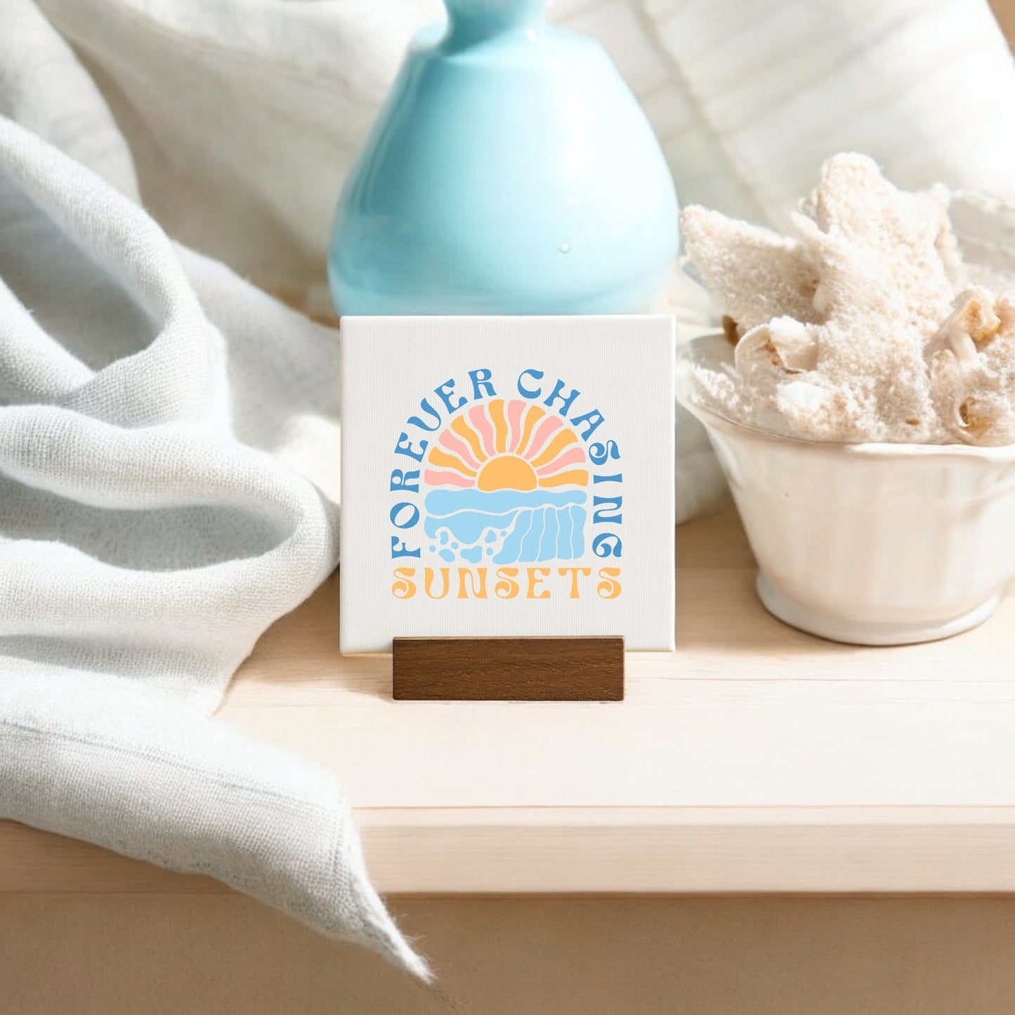 The Forever Chasing Sunsets Mini – Boho Pastel Canvas by Mirabilia Boutique features colorful "Forever Chasing Sunsets" text and a sunset on a wooden stand—perfect mini art for your space.