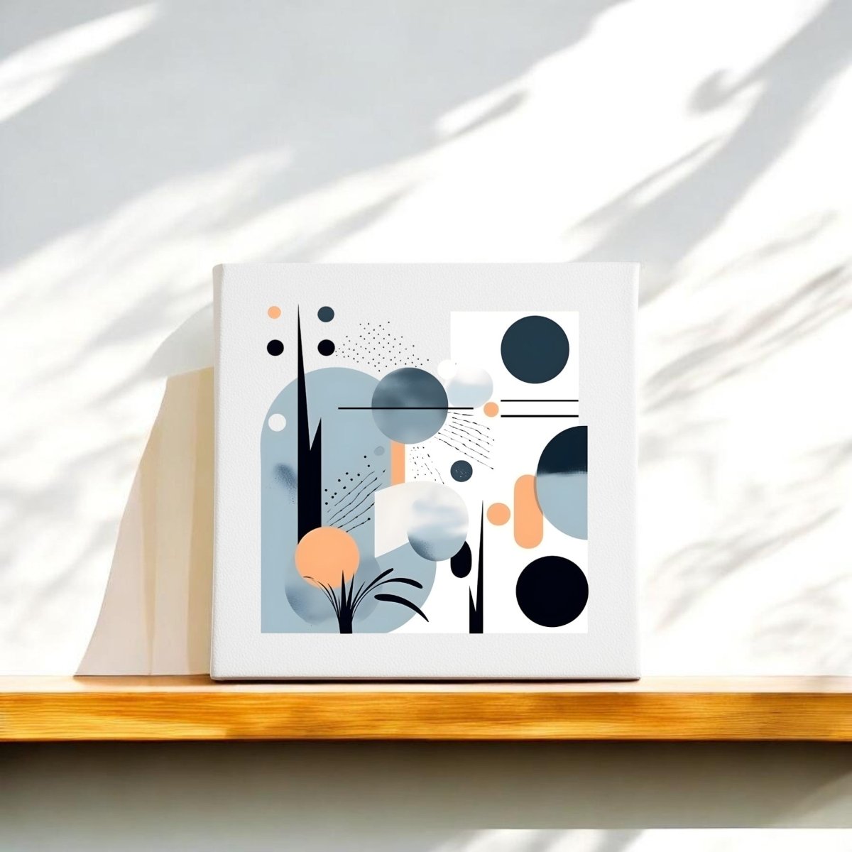 The Coastal Sunrise Mid Century Modern Canvas by Mirabilia Boutique features abstract geometric shapes in black, blue, and orange on white, displayed on a wooden shelf with natural light and shadow accents.