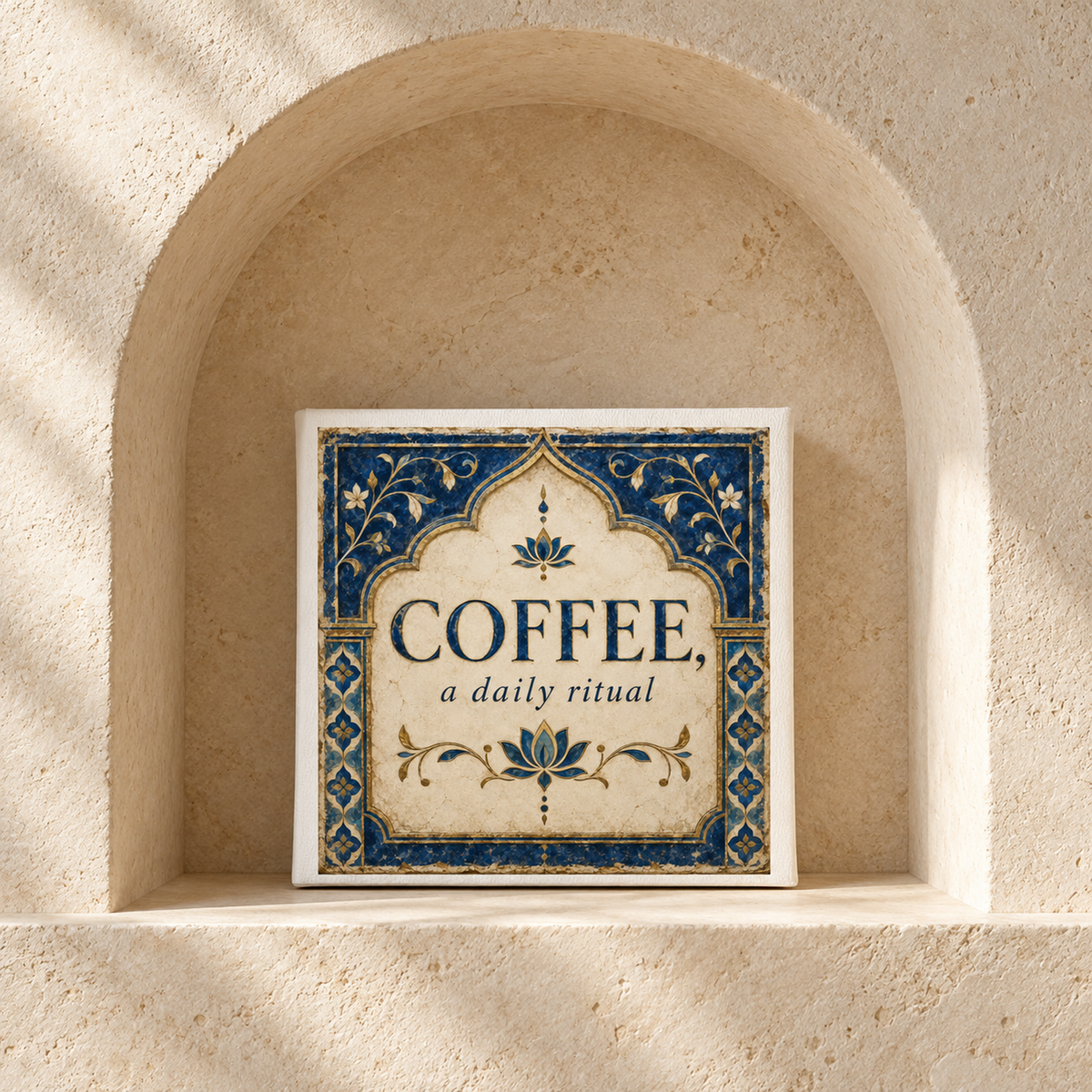 An 8x8 canvas coffee bar sign from Mirabilia Boutique, featuring blue and gold patterns and the phrase “Coffee, A Daily Ritual,” adds a decorative touch to your kitchen. Part of the Lapis & Lotus collection, it sits beautifully on a beige stone shelf within a recessed arch, highlighted by natural sunlight—perfect as wall art for coffee lovers.
