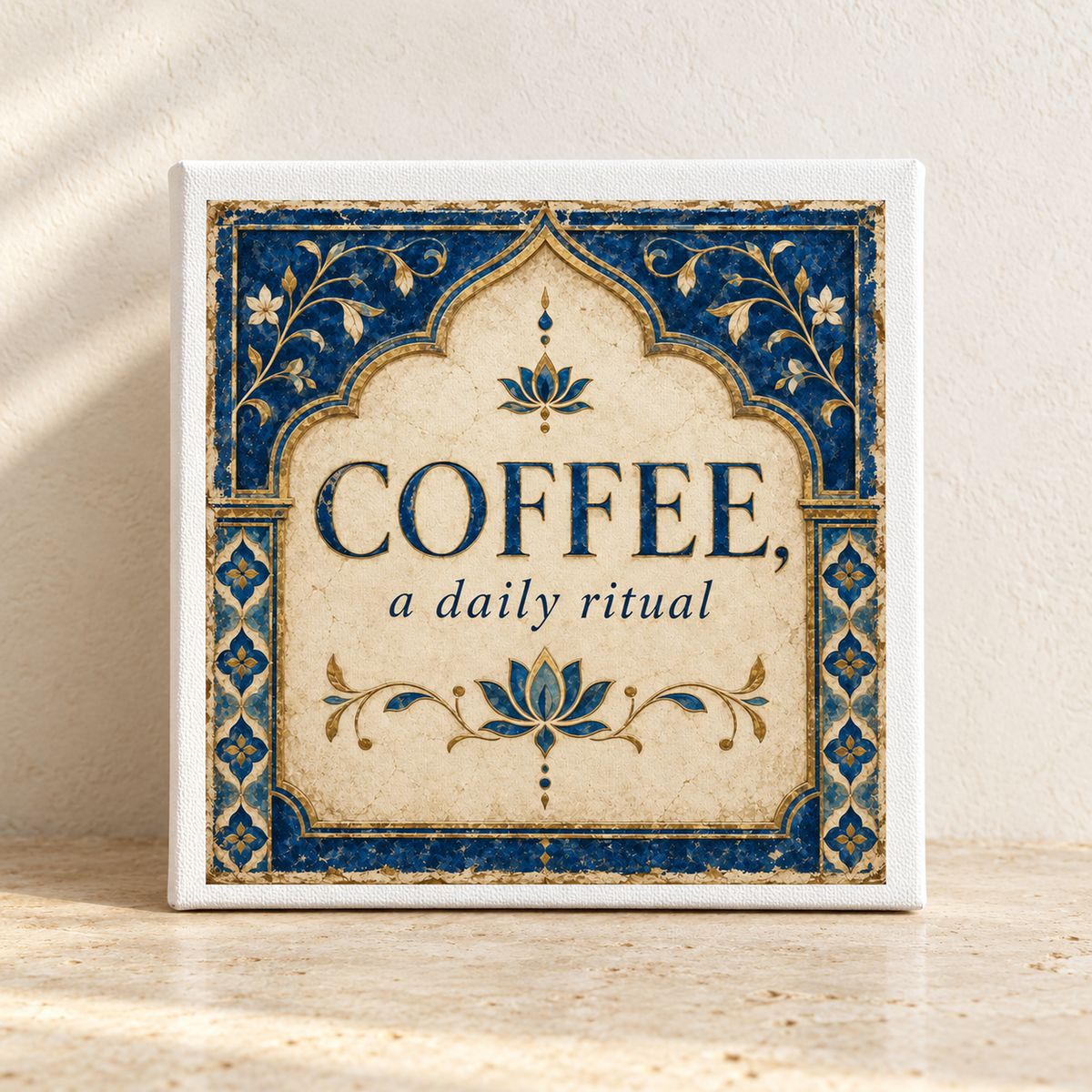 A decorative 8x8 canvas sign from Mirabilia Boutique, featuring elegant “COFFEE, a daily ritual” lettering and stylish blue floral borders from the Lapis & Lotus collection, rests on a sunlit beige surface—making it the perfect kitchen wall art for coffee décor lovers.