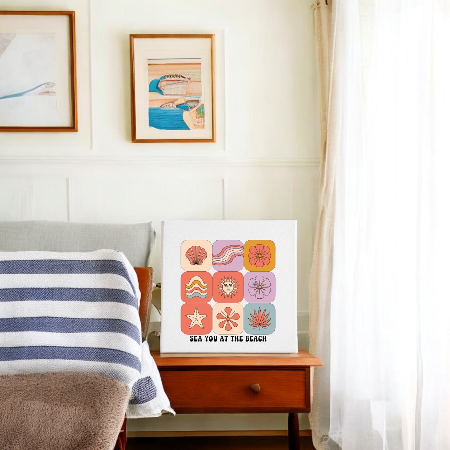 A cozy bedroom features the Sea You at the Beach Canvas – Retro Coastal Wall Art by Mirabilia Boutique above the bed. Light streams in, highlighting a striped blanket and beachy decor for a retro summer vibe.