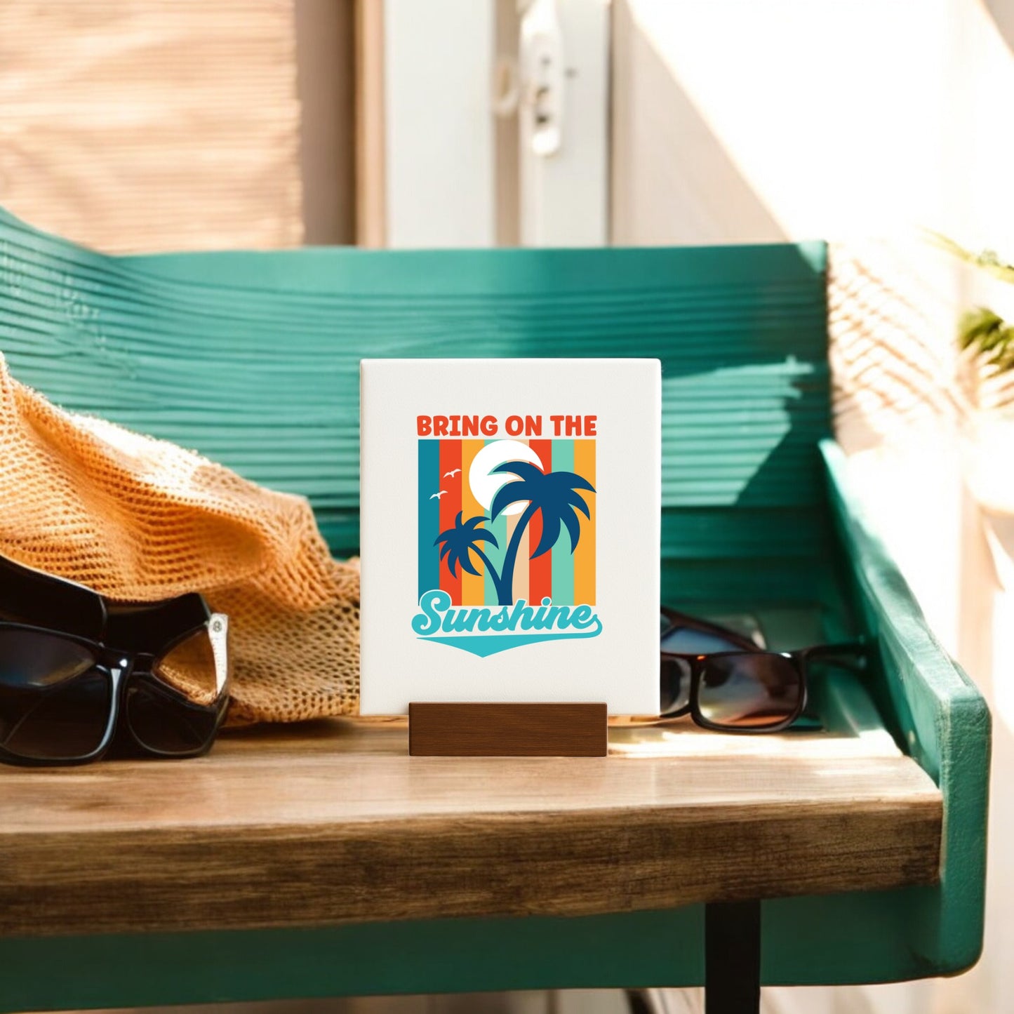 The Mirabilia Boutique “Bring on the Sunshine Canvas – Retro Palm Tree Art” sits on a wooden tray beside black sunglasses and an orange knit, sunlight streaming in—ideal for coastal decor or beach-inspired home accents.