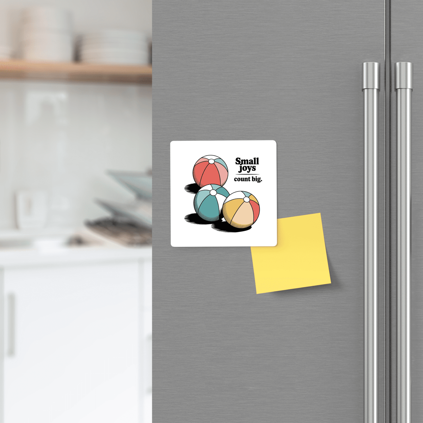 The Small Joys Count Big Magnet – Retro Summer Fridge Art from Mirabilia Boutique, featuring three retro beach balls and an uplifting phrase, adds a cheerful pop of color to your fridge—perfect summer decor beside notes in your kitchen.