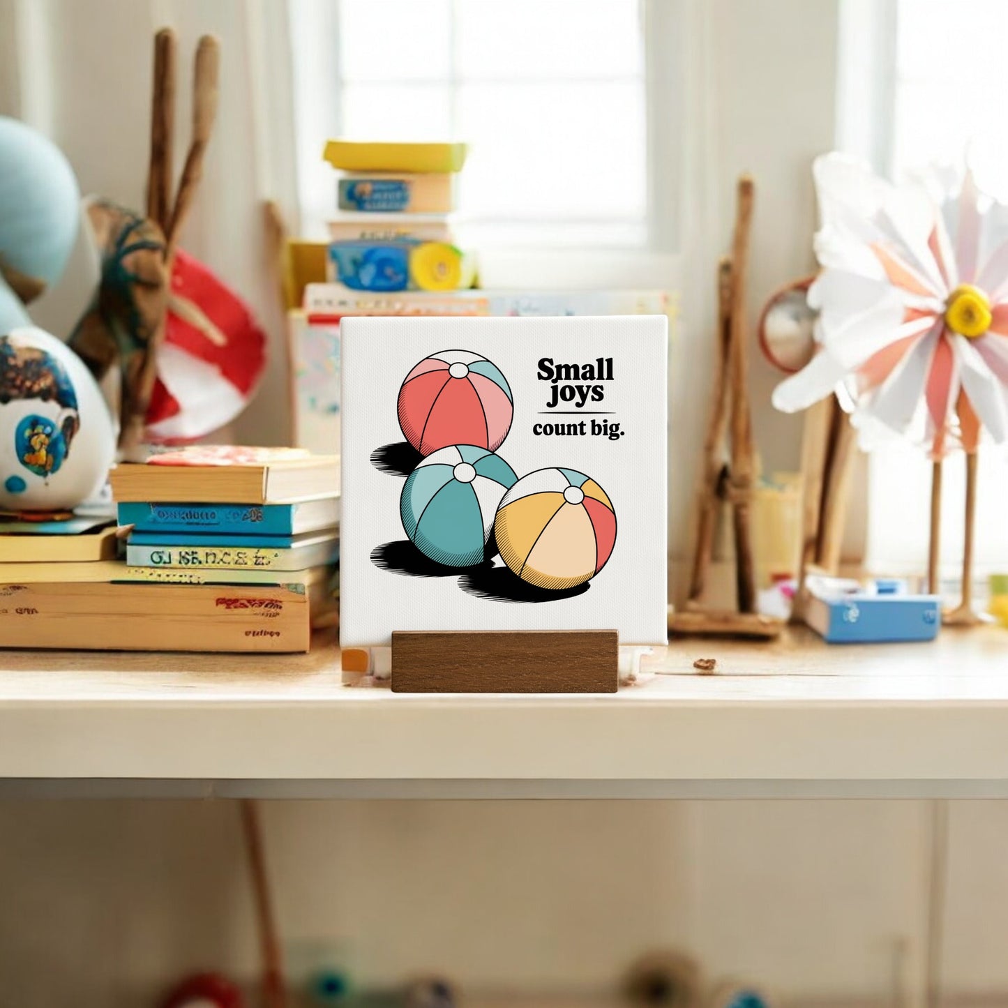 The Small Joys Count Big Mini Canvas – 4x4 Summer Desk Sign by Mirabilia Boutique features three colorful beach balls and cheerful text on a wooden stand, making it a perfect summer home decor accent for your desk or shelf.