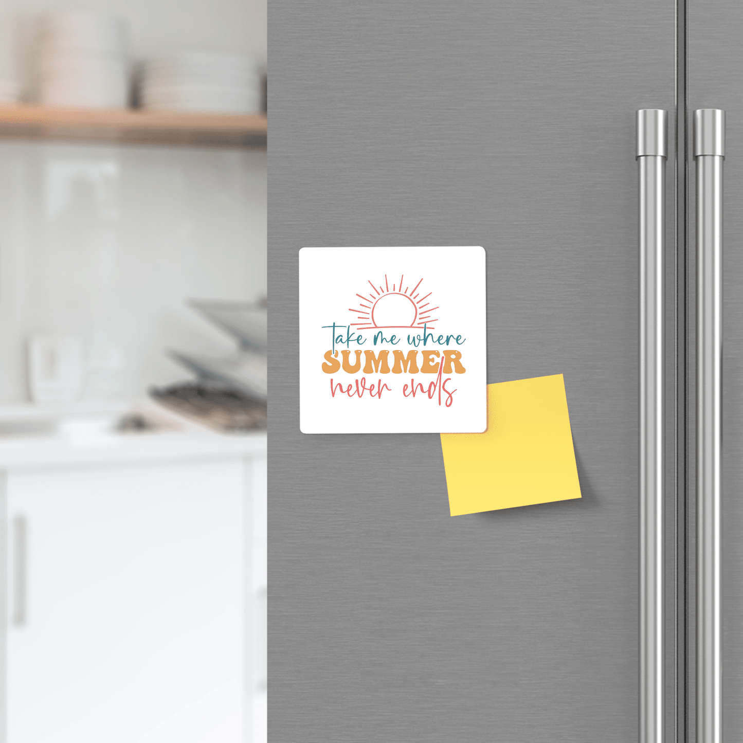 A brightly colored "Take Me Where Summer Never Ends" magnet by Mirabilia Boutique decorates a fridge door beside a blank yellow sticky note, with a softly blurred kitchen counter in the background.