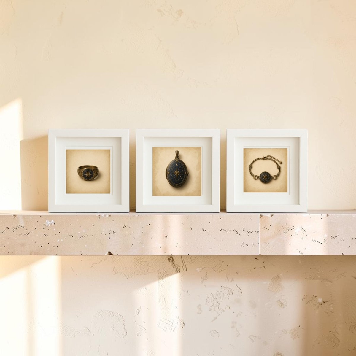 Three framed “The Wayfinder” antique pocket watches by Mirabilia Boutique, each featuring a subtle star compass motif, along with a matching watch chain, are displayed on a light stone mantel against a beige wall, with sunlight casting soft shadows.