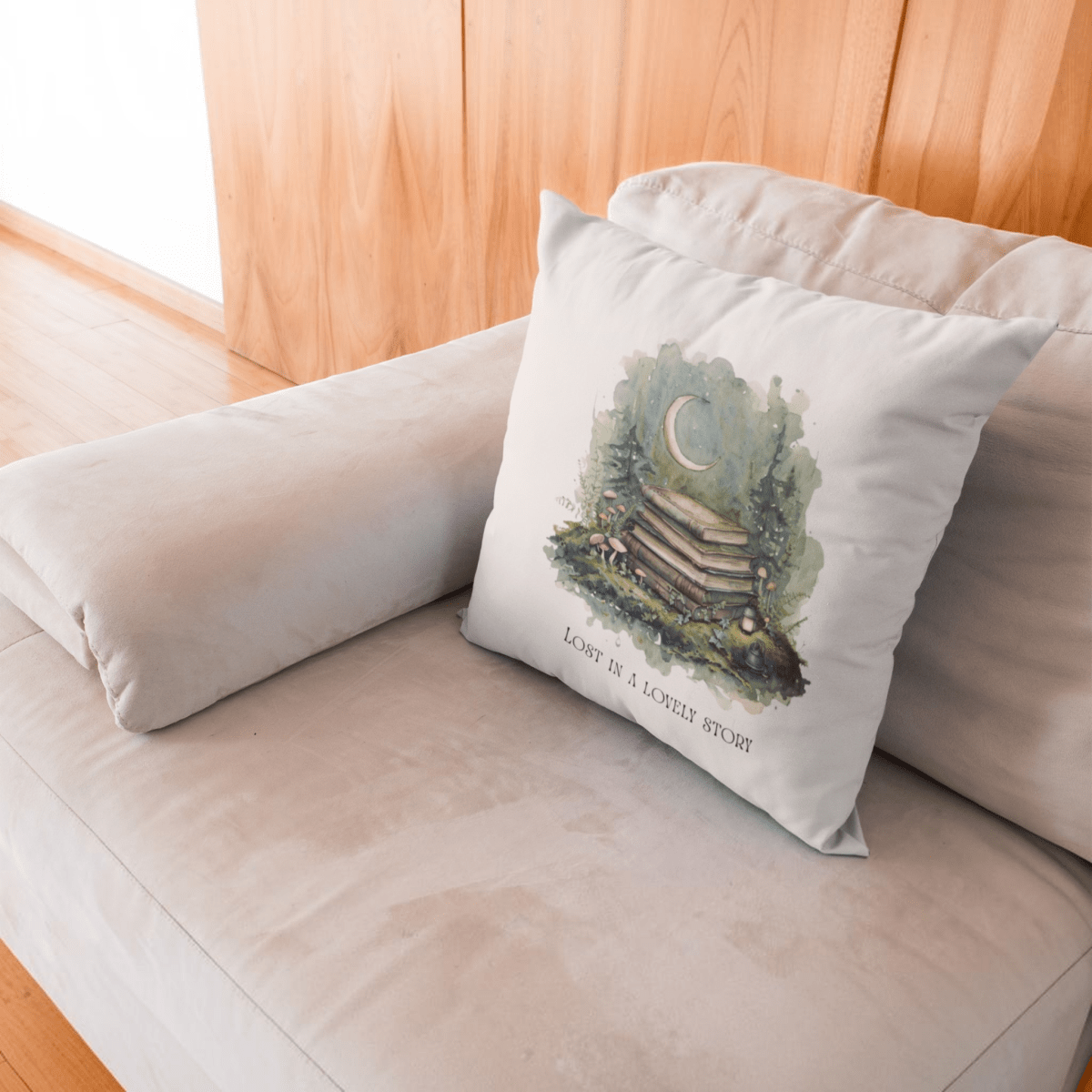 The Lost in a Lovely Story Throw Pillow by Mirabilia Boutique, featuring a white cover adorned with a watercolor illustration of books, trees, and a crescent moon alongside the text “LOST IN A LOVELY STORY,” rests on a light beige couch against a wooden wall—an ideal cottagecore decor accent for any cozy reading nook.