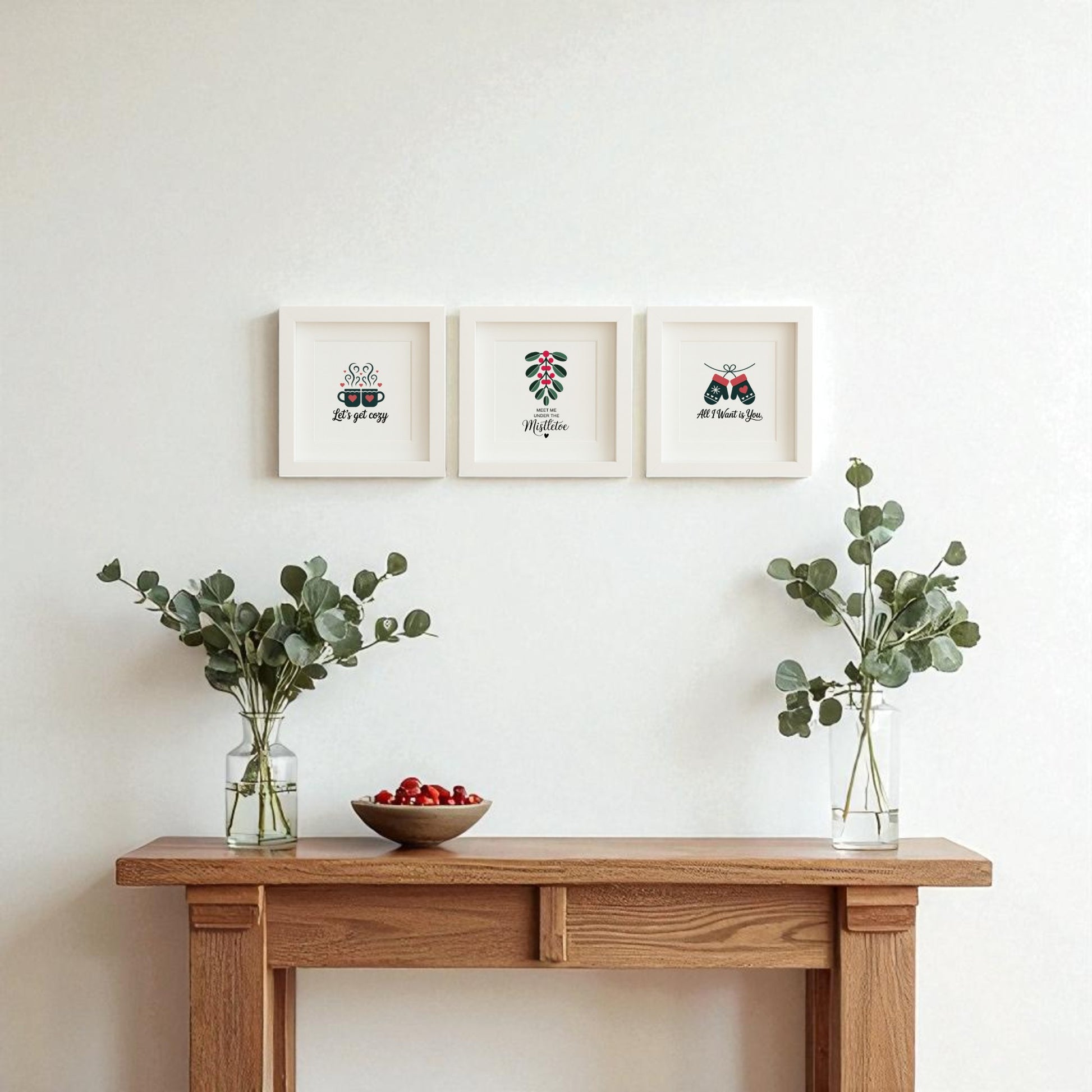 A wooden console table holds vases and cherries, while above, the Romantic Holiday Wall Art Trio | 5x5 Framed Gift Set from Mirabilia Boutique adds a minimalist, romantic touch—perfect as a couple’s gift or festive holiday wall decor.