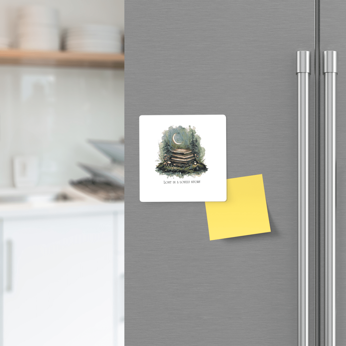 A refrigerator with the Lost in a Lovely Story Book Lover Magnet by Mirabilia Boutique—a square magnet featuring stacked books and a yellow sticky note—displayed on its door. The kitchen background includes shelves with dishes.
