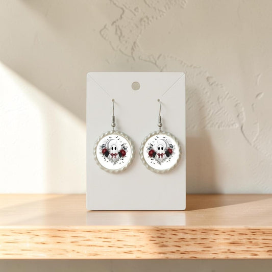 A pair of Crescent Moon Lace Ghost Scalloped Earrings from Mirabilia Boutique, displayed on a white card and set on a wooden surface with sunlight casting shadows, their vintage-inspired design evoking delicate charm.