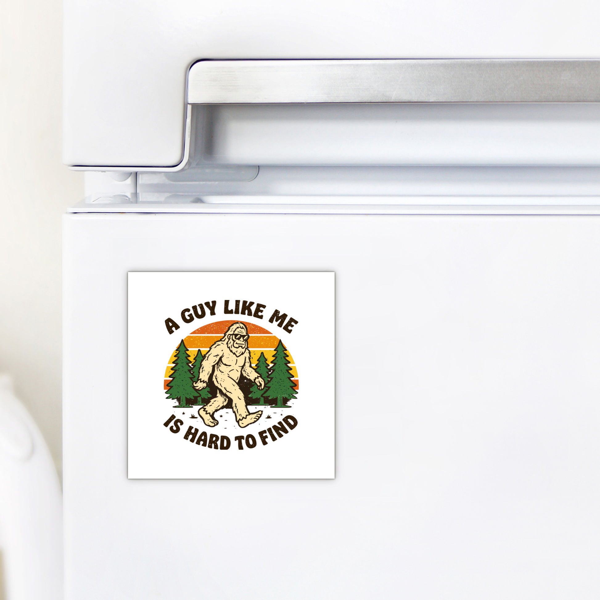 A white fridge displays the Mirabilia Boutique Funny Bigfoot Magnet, showing Bigfoot walking before trees and a sunset. The text reads, "A GUY LIKE ME IS HARD TO FIND." Great for Sasquatch decor fans.
