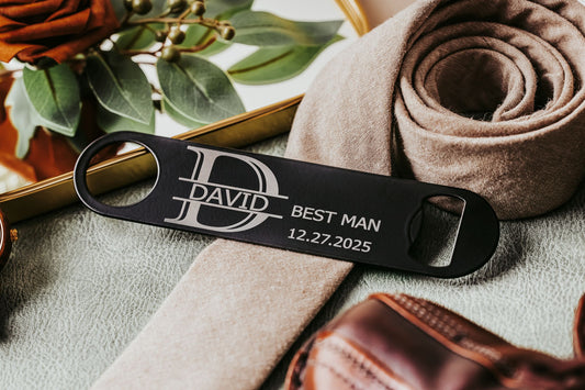 The Mirabilia Boutique Engraved Flat Metal Bottle Opener, etched with "DAVID BEST MAN 12.27.2025," rests among elegant decor—a classy groomsmen gift or custom wedding favor for your big day.