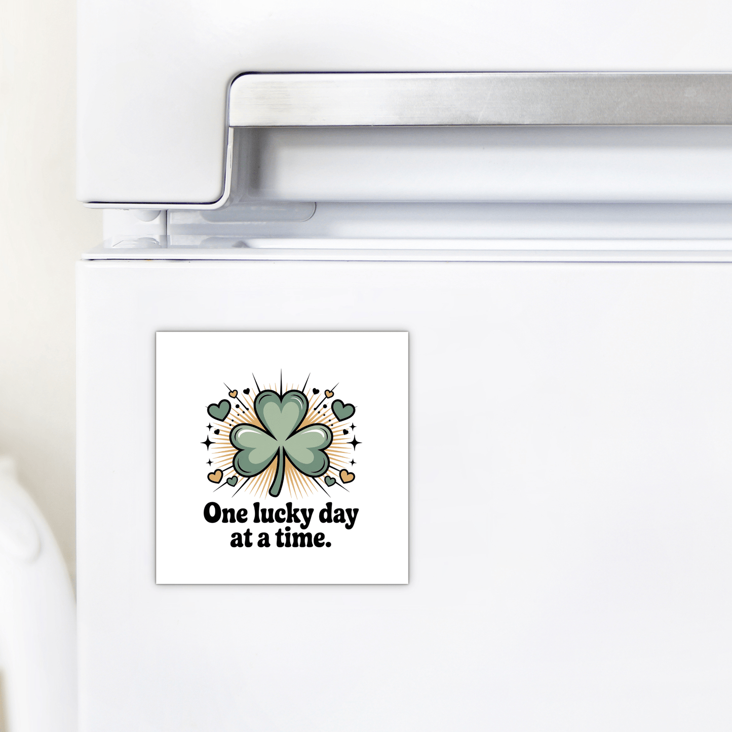A white refrigerator features the Mirabilia Boutique "One Lucky Day at a Time Magnet," decorated with a green four-leaf clover, small hearts, sparkles, and the phrase "One lucky day at a time.