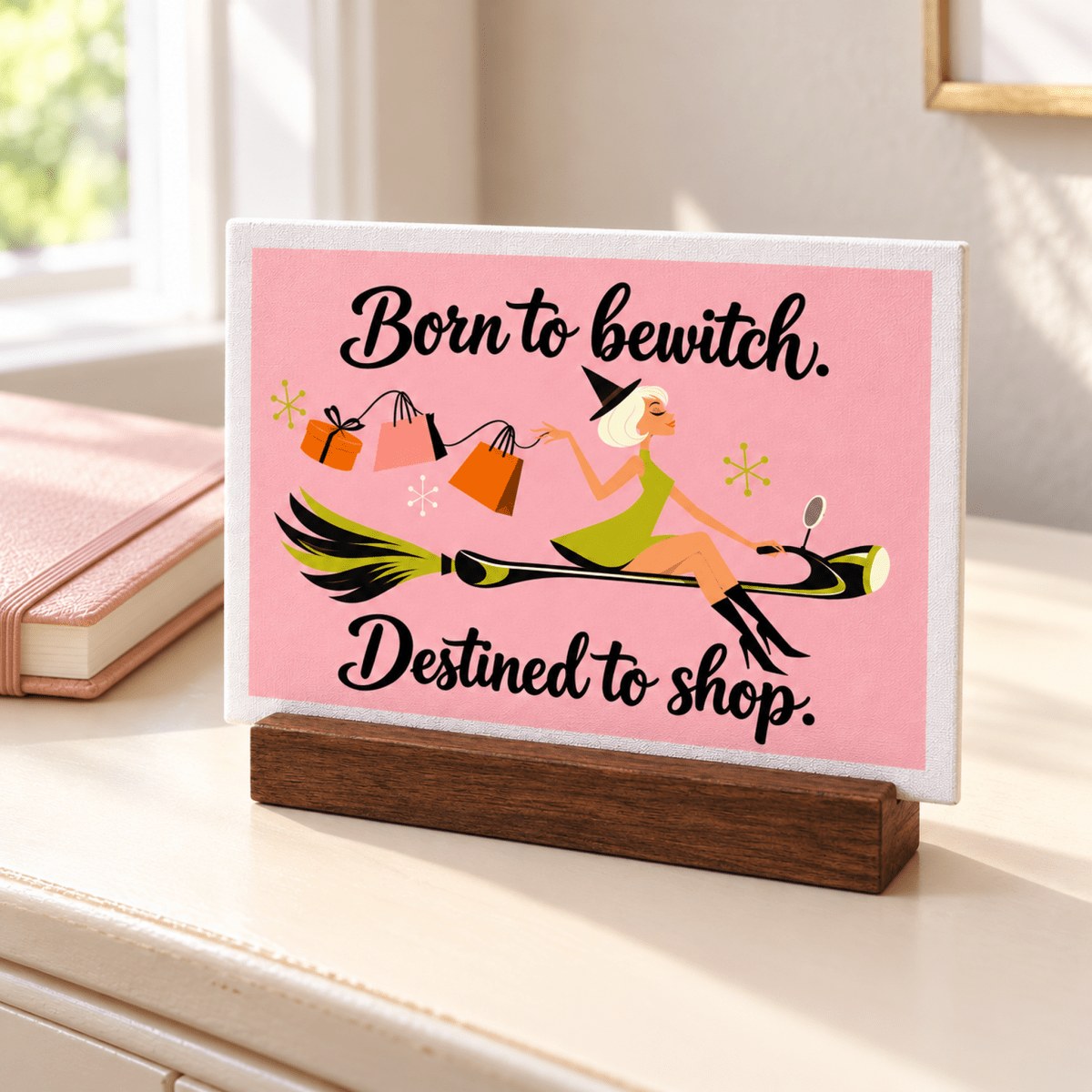 A Little Retail Magic Mini Sign | Fall Vibes featuring mid-century art of a witch flying on a broomstick with shopping bags, on a wooden base with the text “Born to bewitch. Destined to shop.”