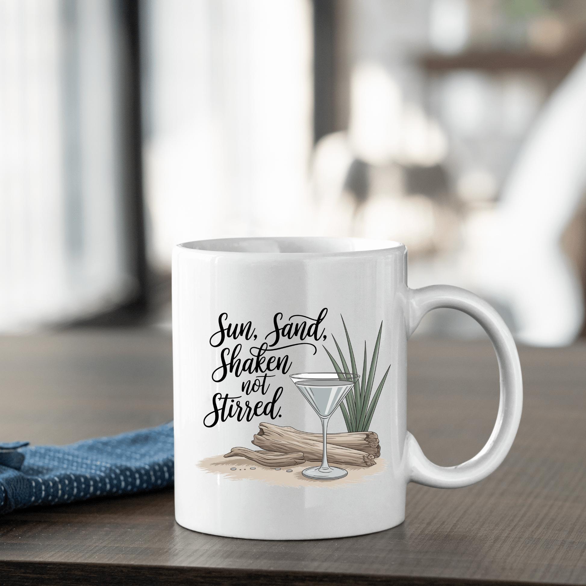 The Sun, Sand, Shaken Not Stirred Mug – Coastal Coffee Vibe by Mirabilia Boutique features a martini glass, driftwood, and grass design with the phrase “Sun, Sand, Shaken not Stirred,” perfect for adding beach house charm.