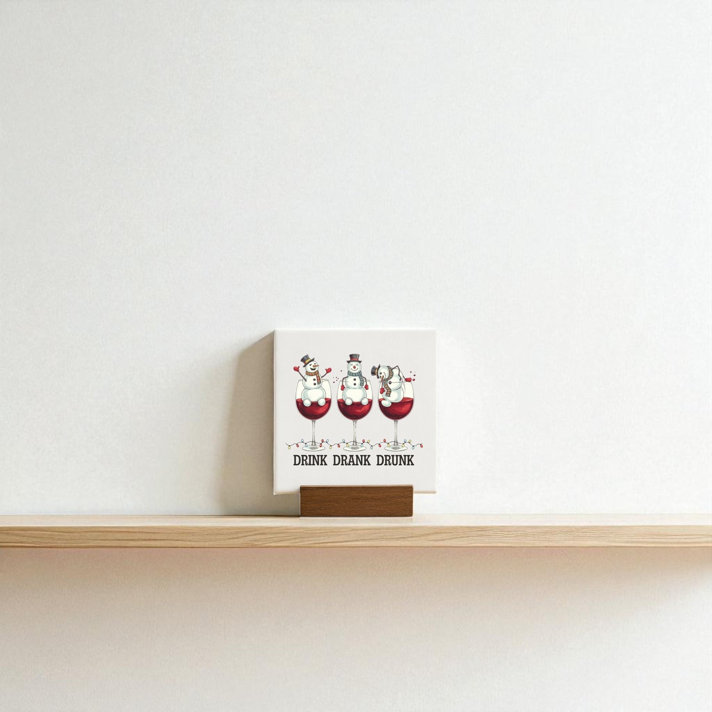 The Drink Drank Drunk Mini Canvas by Mirabilia Boutique is a 4x4 funny Christmas sign featuring three cartoon snowmen in wine glasses with the caption “DRINK DRANK DRUNK”—a perfect festive decor or wine lover gift.