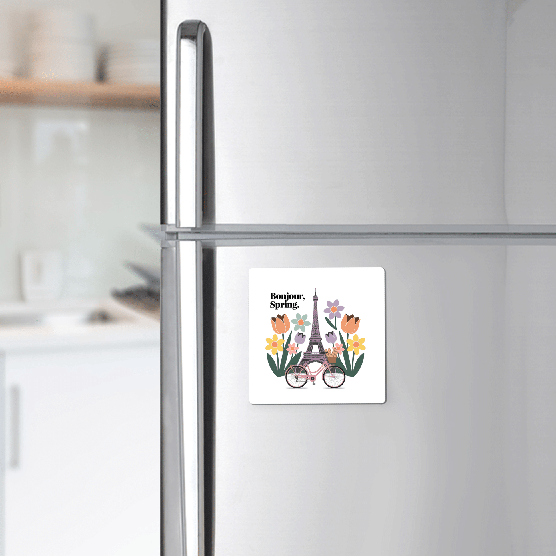 The Mirabilia Boutique Bonjour Spring Magnet – Paris Bicycle & Floral Charm adds Parisian flair to your kitchen, featuring the Eiffel Tower, flowers, and a bicycle on a silver refrigerator with "Bonjour, Spring.